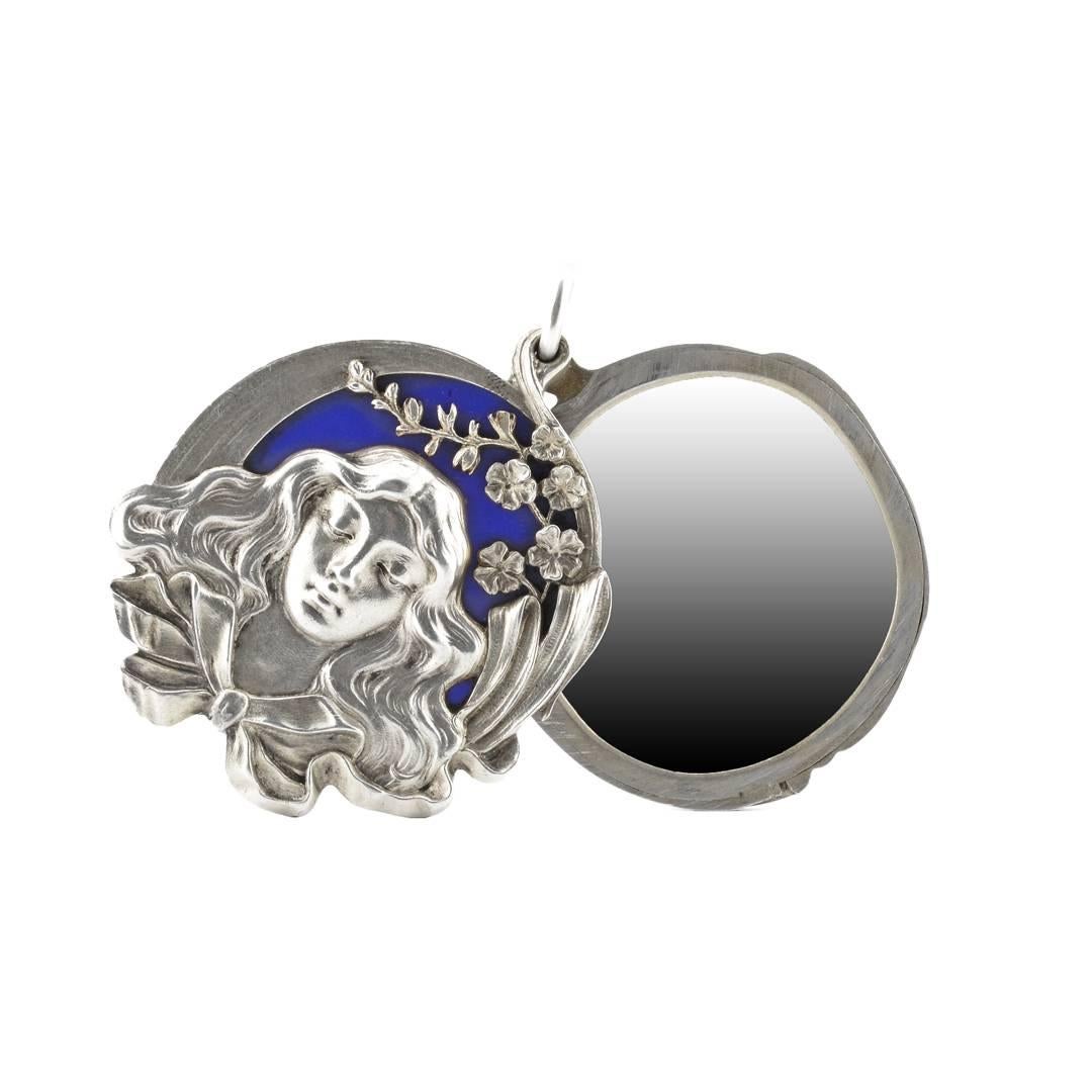 A rare Fabergé Art Nouveau silver and enamel slide locket pendant mirror, Moscow, 1899-1908. The front is set with a cast and chased silver mount depicting a maiden with flowing hair and curling floral ornament, all against a blue matte enamel
