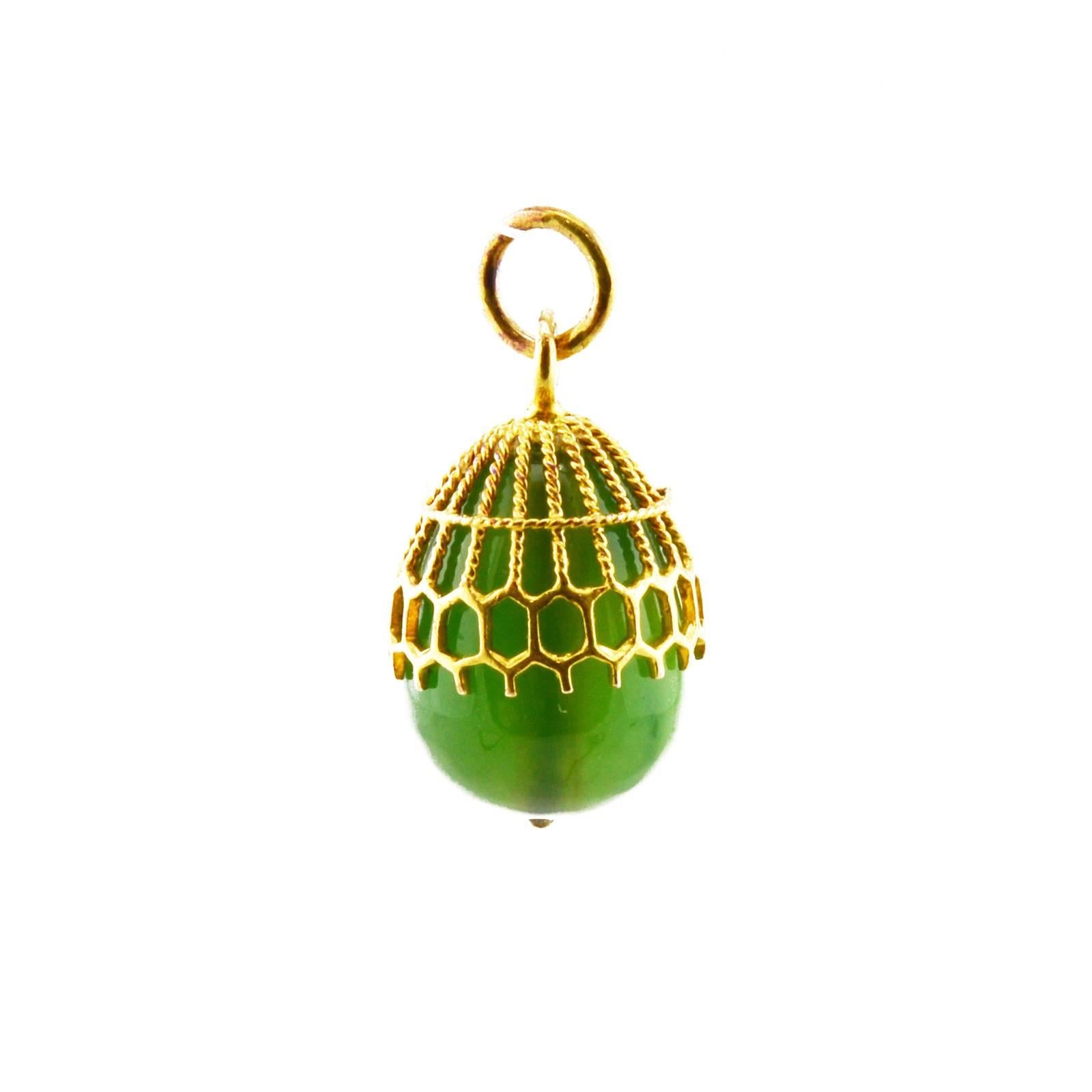 A Russian gold and nephrite miniature pendant Easter egg, St. Petersburg, 1908-1907. The carved nephrite egg held in a gold honeycomb and twisted cable cagework mount, struck with assayer's mark for the St. Petersburg district and 56 gold standard