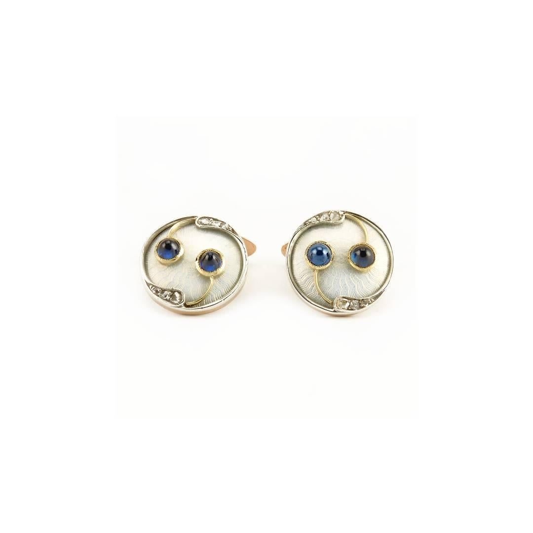 A pair of antique late Imperial Russian diamond, sapphire, gold and guilloché enamel cufflinks, Saint Petersburg, circa 1908-1917. The circular links enameled opalescent pearl white over a wavy, engine-turned ground, the borders with rose cut