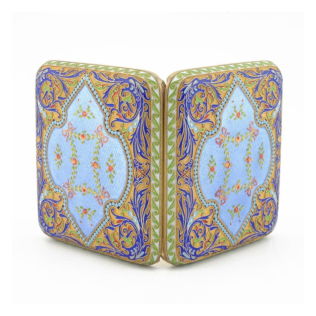 A Russian gilded silver, cloisonné, and guilloché enamel cigarette case, Grachev Brothers, St. Petersburg, 1904-1908. The exterior of the rounded rectangular case decorated with a shaped shield enameled translucent sky blue over an engine-turned