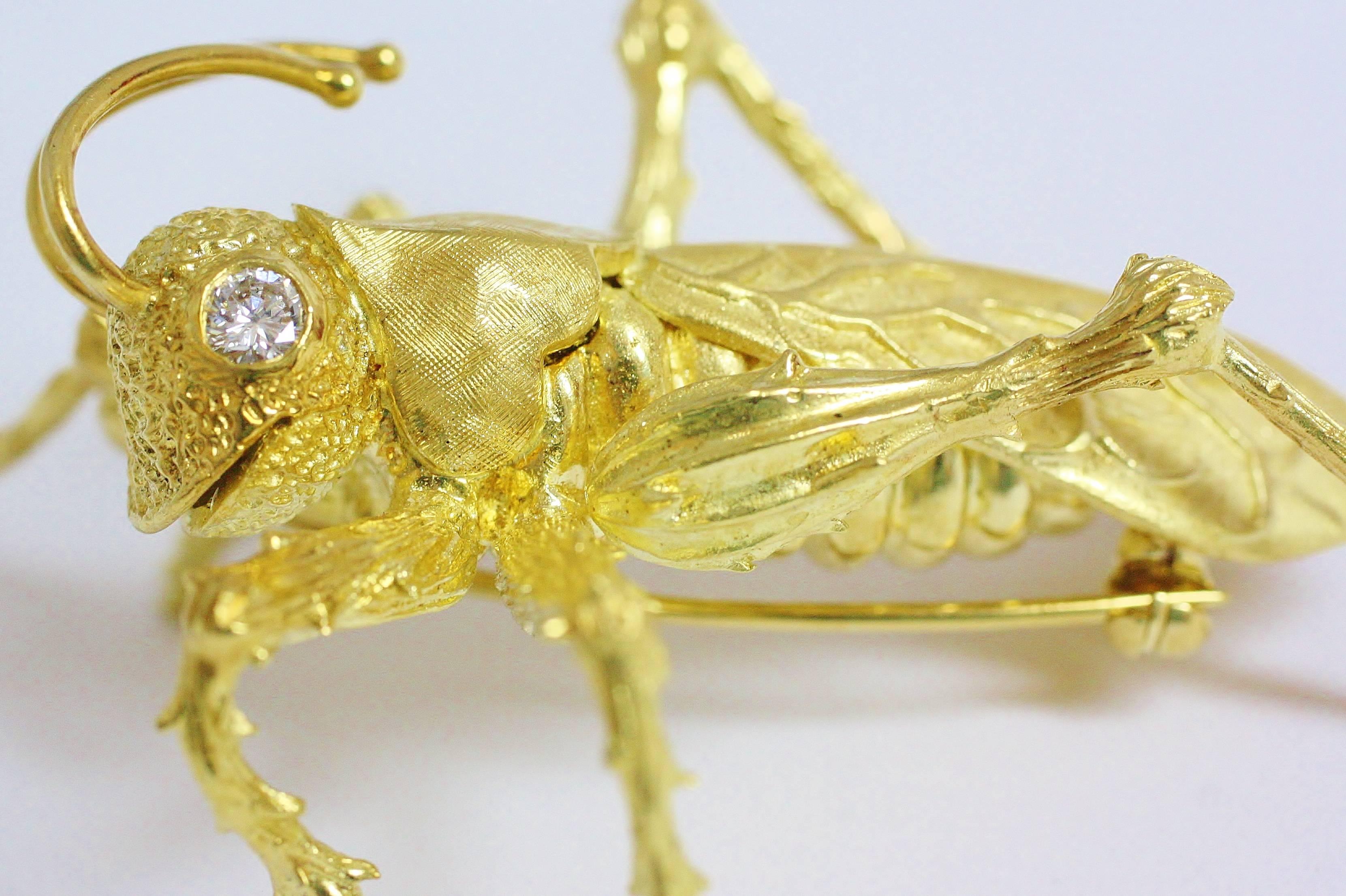 Designed and created by Kurt Wayne, this grasshopper brooch features lifelike details captured in the small marks of its antennae to the veins in its wings. It is almost as if this piece was a real grasshopper dipped in liquid gold.For its eyes,