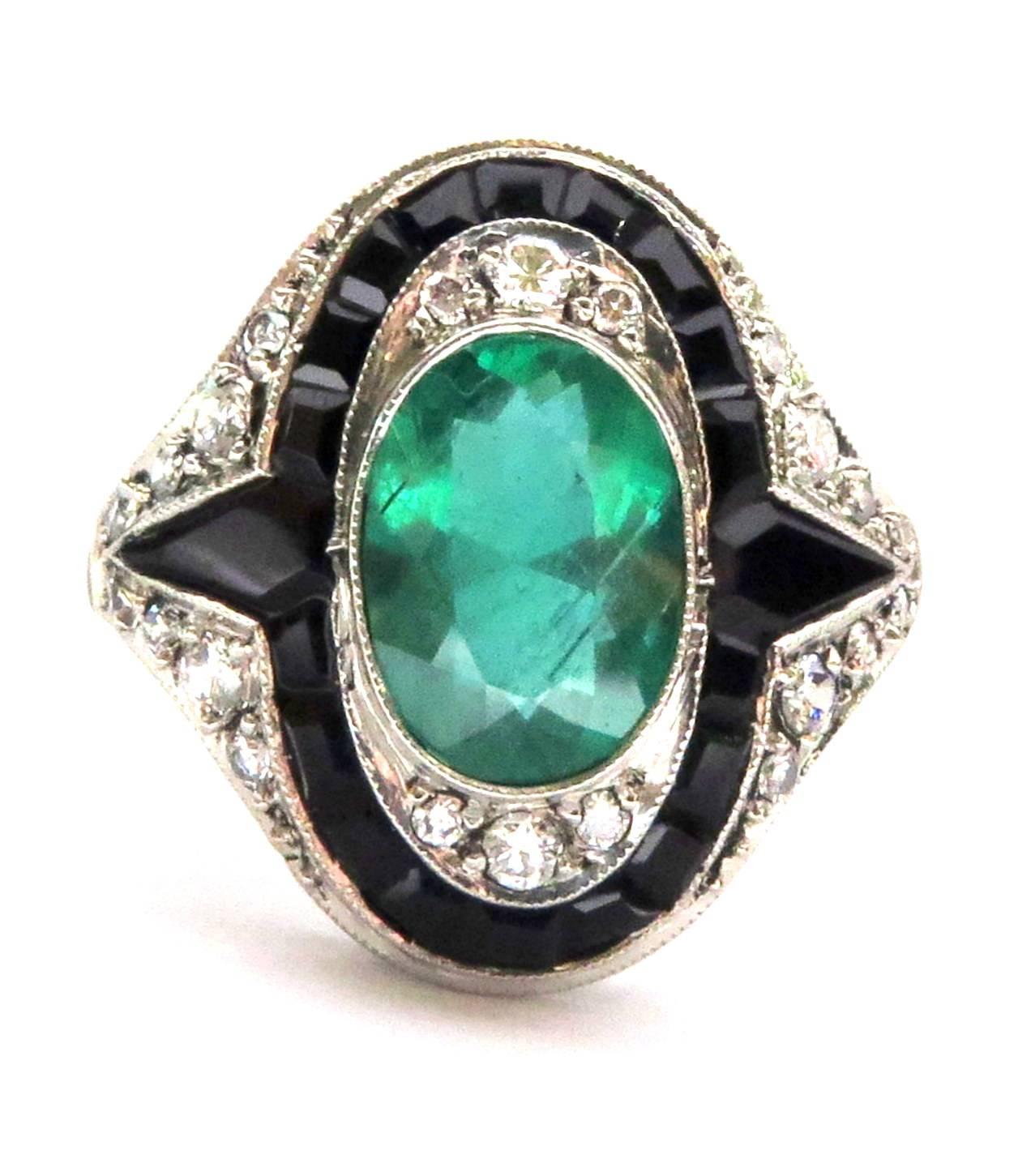 This gorgeous platinum large oval bezel set emerald ring is surrounded by diamonds and calibrated onyx. This versatile ring which  can be dressed up or down has a very important look.  The emerald is approx 2 1/2 carats.
This ring is a size 7 and
