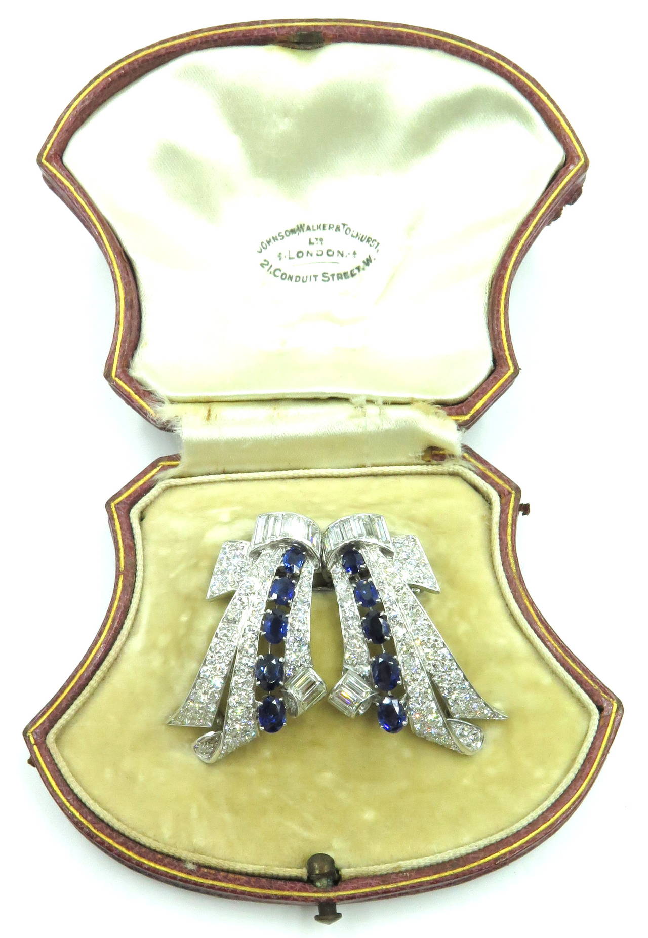 These beautiful platinum diamond sapphire dress clips were retailed by Johnson Walker & Tolhurst LTD London. These double dress clips boast a ribbon motif. They can be worn together as shown thanks to the original detachable appliance allowing them