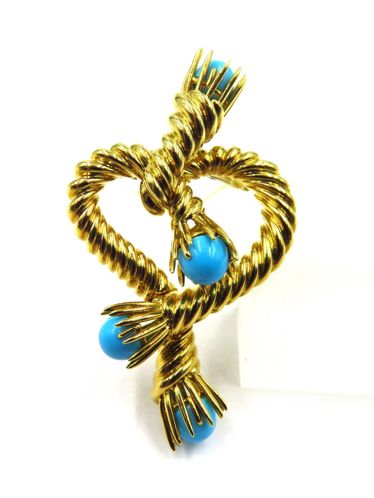 This large romantic roped heart design brooch is accented with 4 turquoise stones. Signed Tiffany & Co Schlumberger Studios 750,  Offered in original box.
