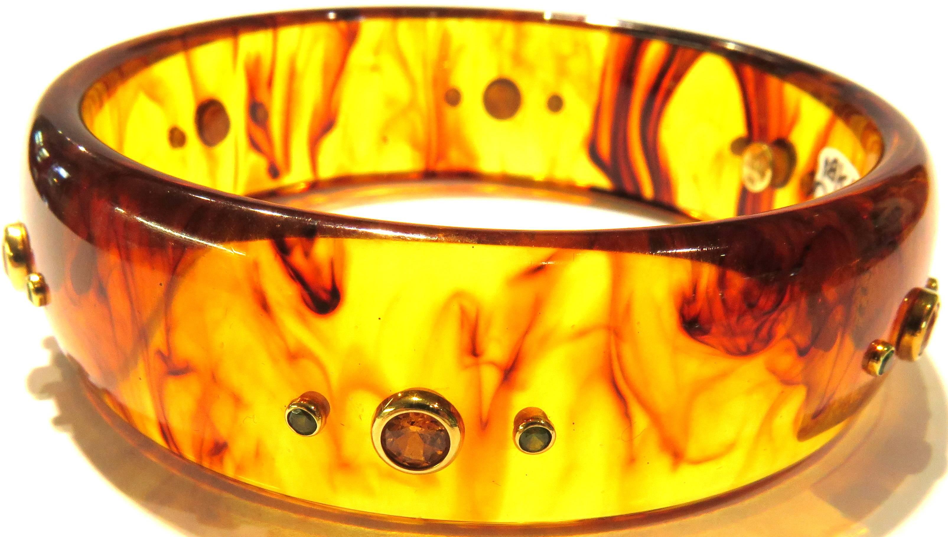 This is a Mark Davis 18k resin/tortoise-Bakelite bangle bracelet. There are 6 sets of 3 gemstone clusters. The signature is found inside the bracelet.
This bracelet measures 2 3/4 inch inside-across the perimeter. 
This bracelet weighs 31.1