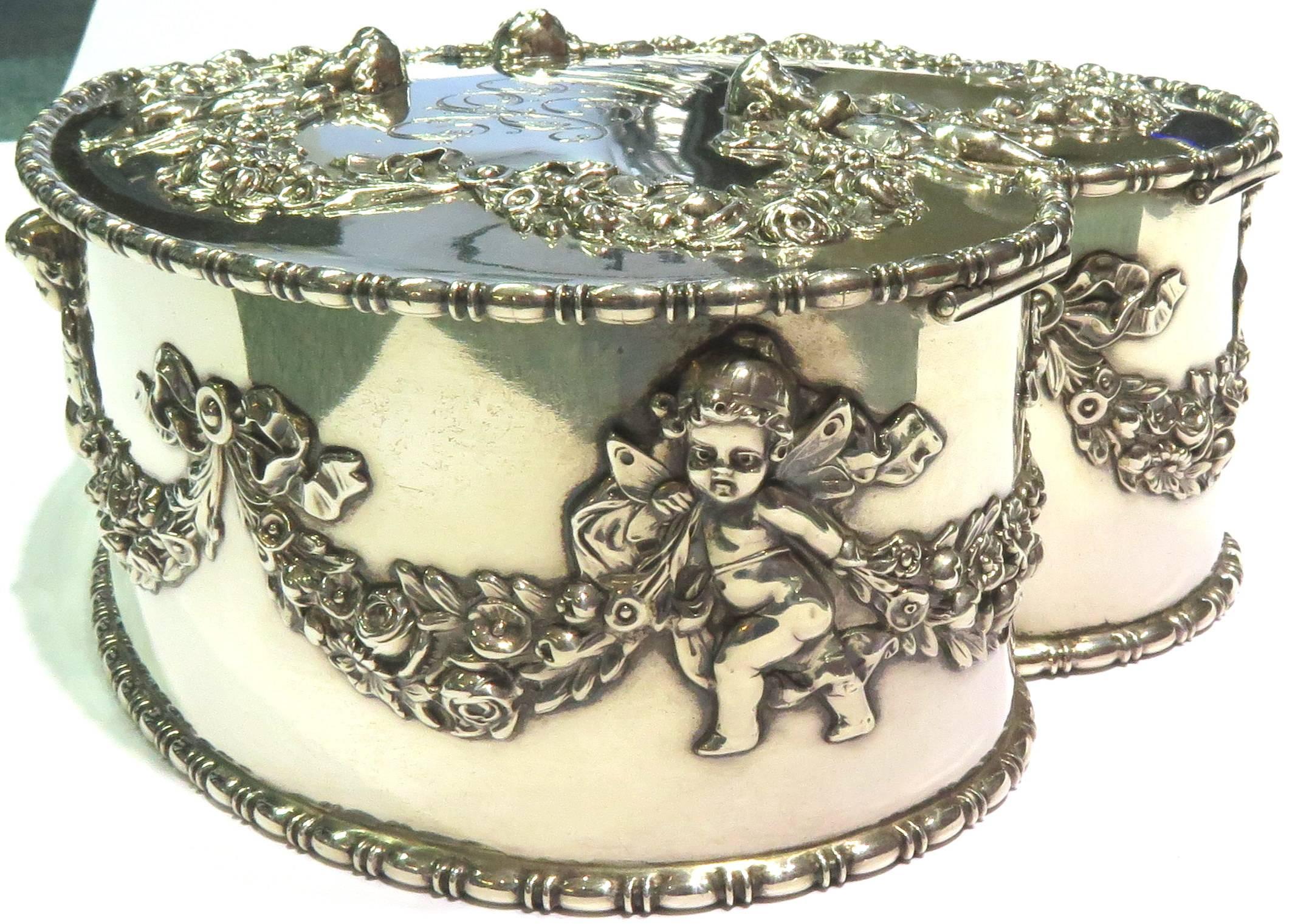 This incredible ornate jewelry box is made by Howard & Co. around the turn of the century. It is in excellent condition with garland being draped by the cherubs.The inside is also in wonderful condition featuring 5 ring slots and a lot of room to
