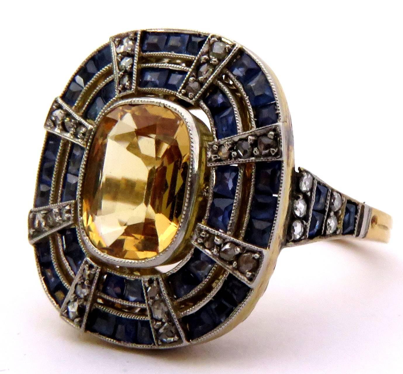 This is the most stunning original Art Deco ring I've seen in a long time. Set in platinum and 18k gold. This ring contains a bezel set yellow sapphire center surrounded by 2 rows of channel set blue sapphires. All the diamonds used as accents are