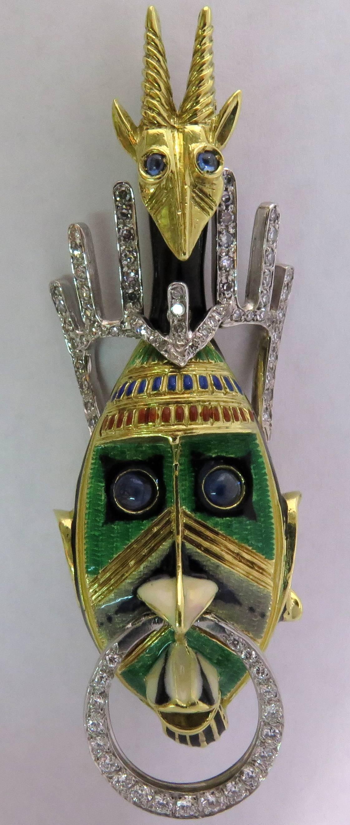 Amazing 18K yellow gold and platinum prong set diamond vividly enameled pin.  This pin is exquisitely detailed with a movable diamond nose ring and figural head dress. Both faces feature cabochon sapphire eyes. If you are looking for the unusual and