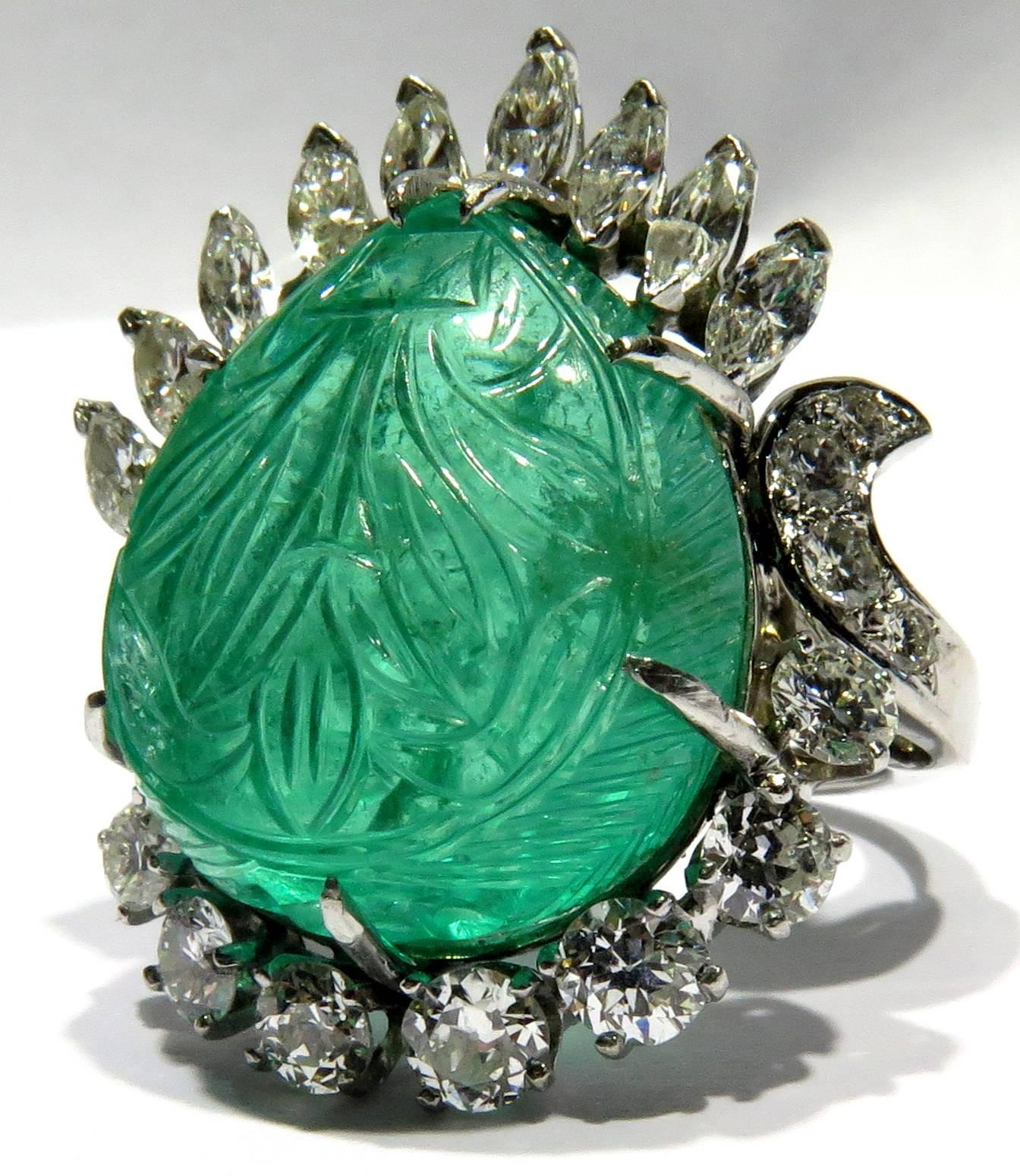 This incredible platinum ring is sure to become your favorite! This amazing flower carved emerald weighs approx 17 carats and is cut in a marquise shape held by 7 prongs. The surrounding diamonds are round and marquise shapes. There are approx 3