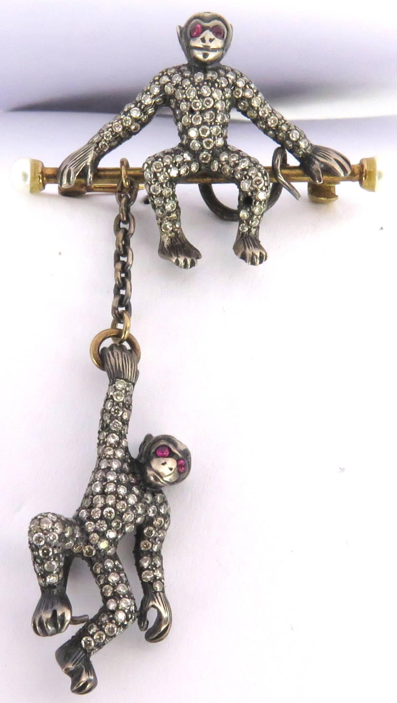This adorable pair of monkeys are so much fun to wear. The detail on their faces are just irresistible! The monkey on top sits upon a gold bar capped with a pearl on each end. The monkey on the bottom swings  from the bar below. Each monkey has
