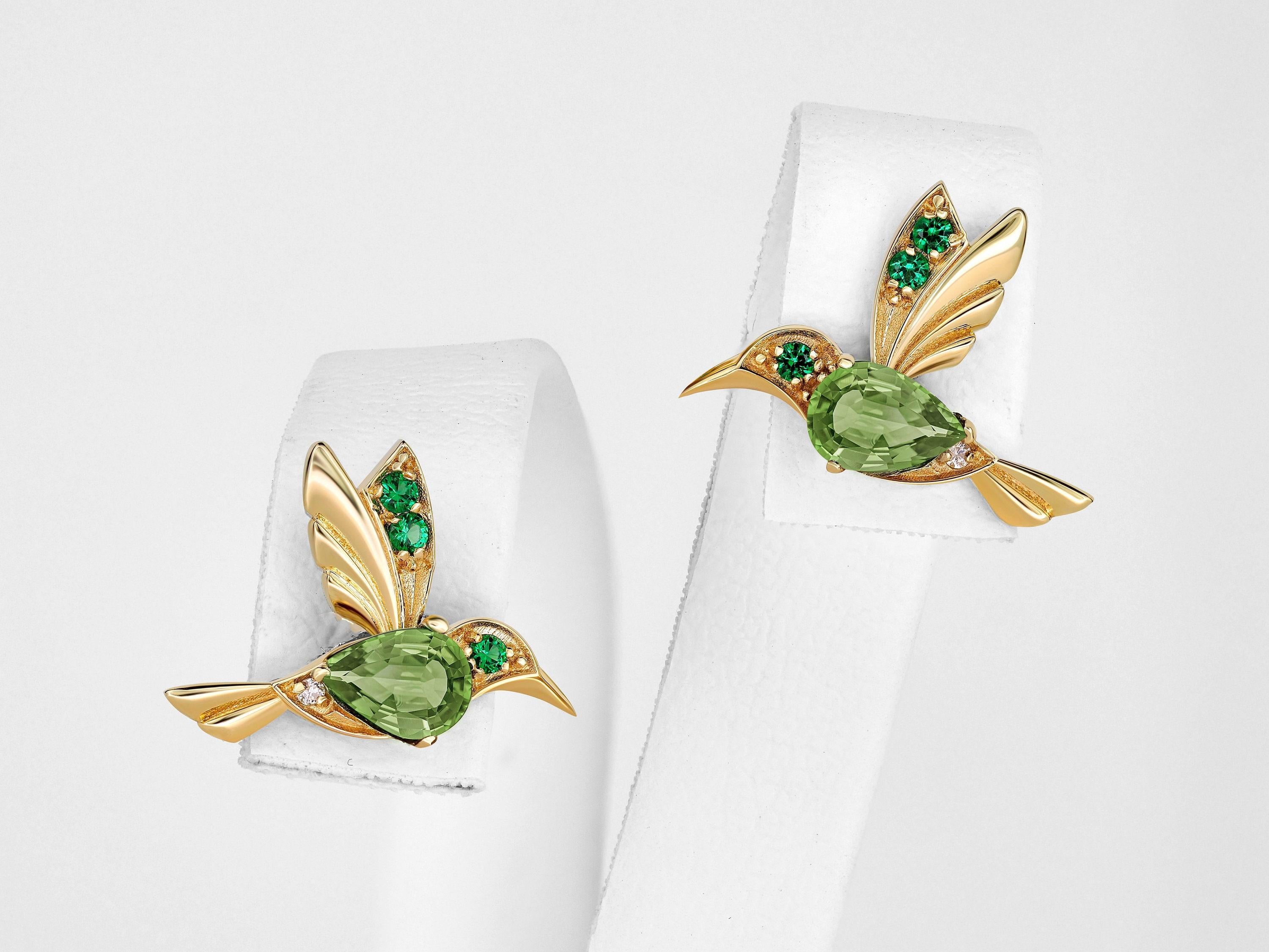 Orecchini a perno in argento 925 con colibrì e peridoto.

Metallo: argento 925
Peso: 2 g.
Dimensioni: 11,73 x 15,85 mm.

Pietre centrali: Peridoti autentici
Taglio: a pera
Peso: circa 1 ct.
Colore: verde mela, verde oliva
Limpidezza: Trasparente con