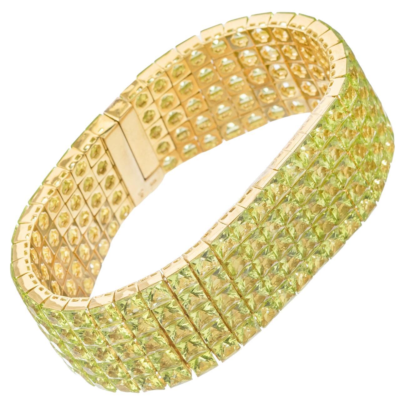 Line bracelet, featuring five rows of faceted square-shaped peridot invisibly-set in 18k yellow gold.  145 peridot weighing approximately 69.30 total carats.  Five diamonds weighing approximately 0.41 total carats.  Clasp is a hidden design with
