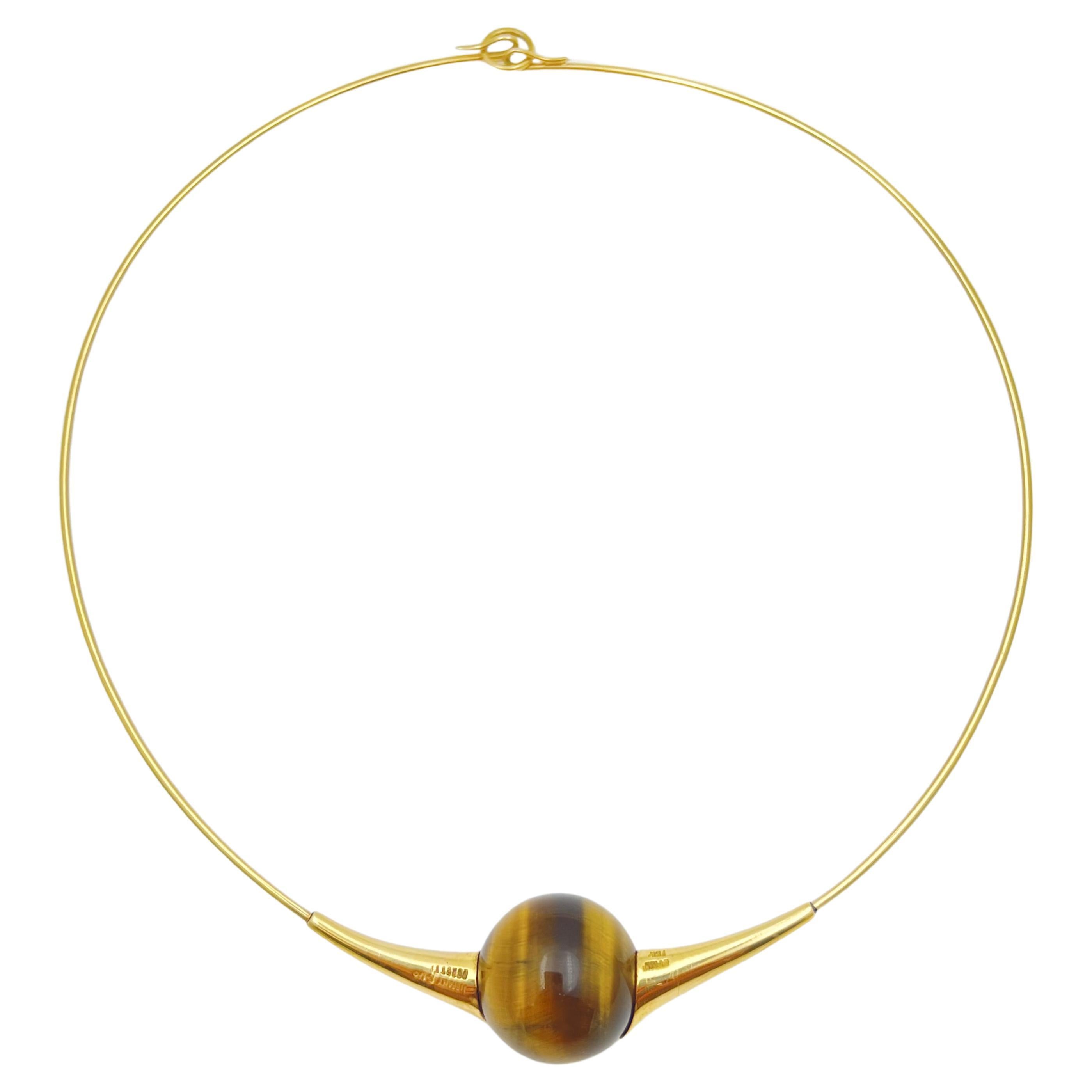 Rare and collectible 1970s design by Elsa Peretti for Tiffany & Co.  18k yellow gold wire collar centering a tiger eye spherical bead measuring 18.25mm in diameter.  Tiger eye bead is a rich golden brown color.  Neck wire has a 16
