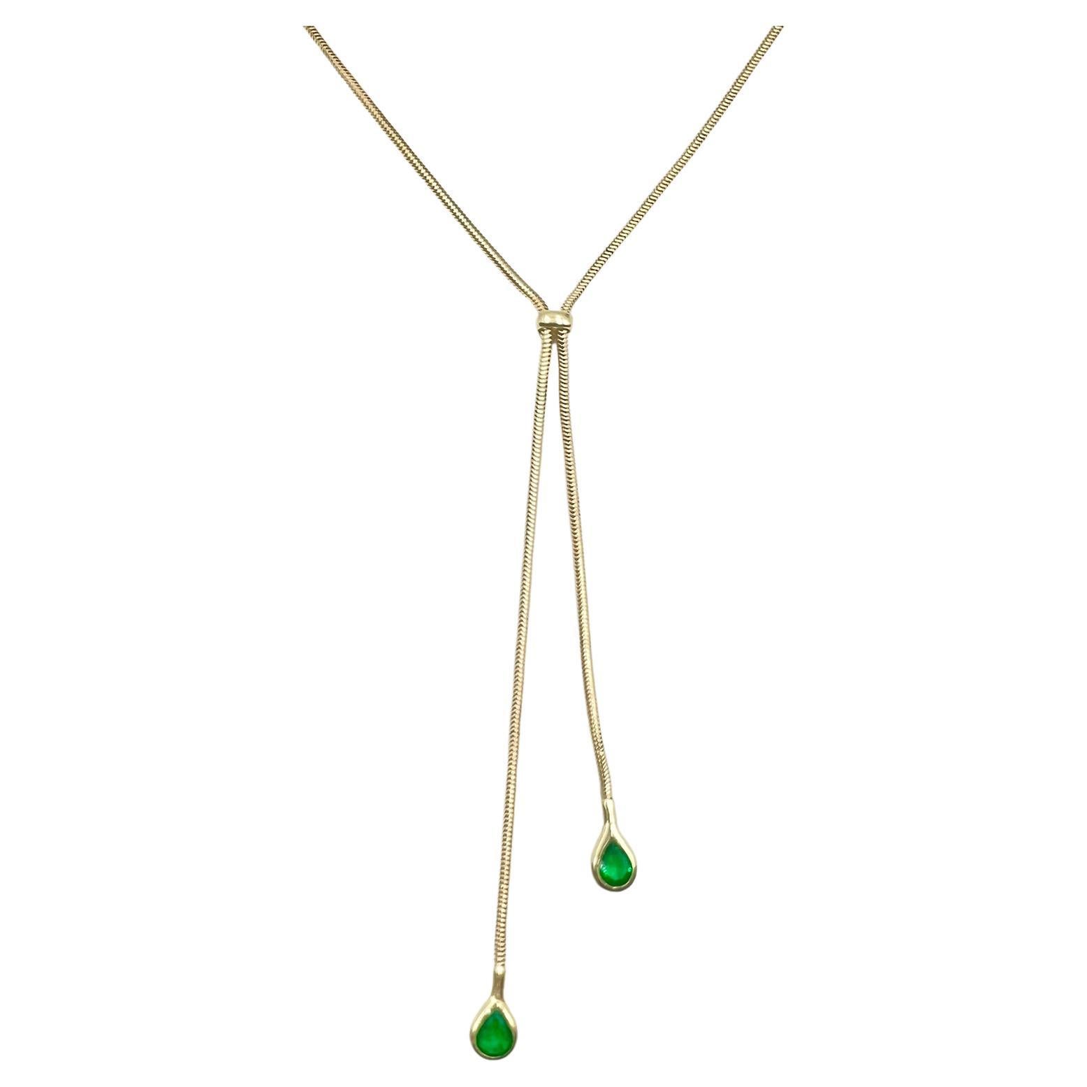 Tiffany & Co. 18k yellow gold snake design link necklace joined in the center with a polished band wrap which adjusts in length for the neck.  Two bezel-set pear-shaped faceted natural Colombian emeralds, in a vibrant green color, adorn the tips. 
