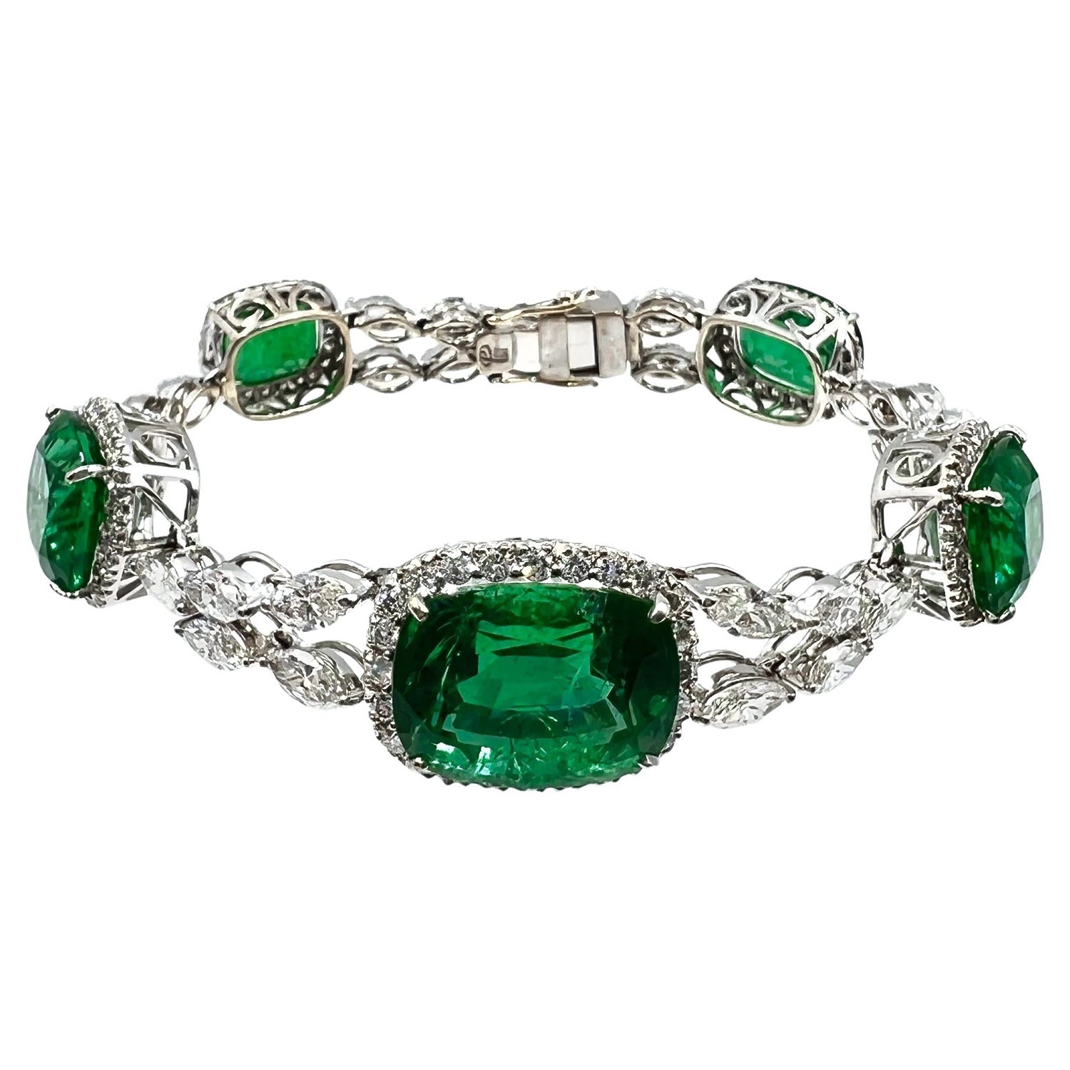 Emerald and diamond bracelet, featuring five cushion-shaped natural emeralds weighing 35.52 total carats.  The five emeralds graduate in size from the center and are each framed by round brilliant-cut diamonds.  Joined by twenty-nine marquise and