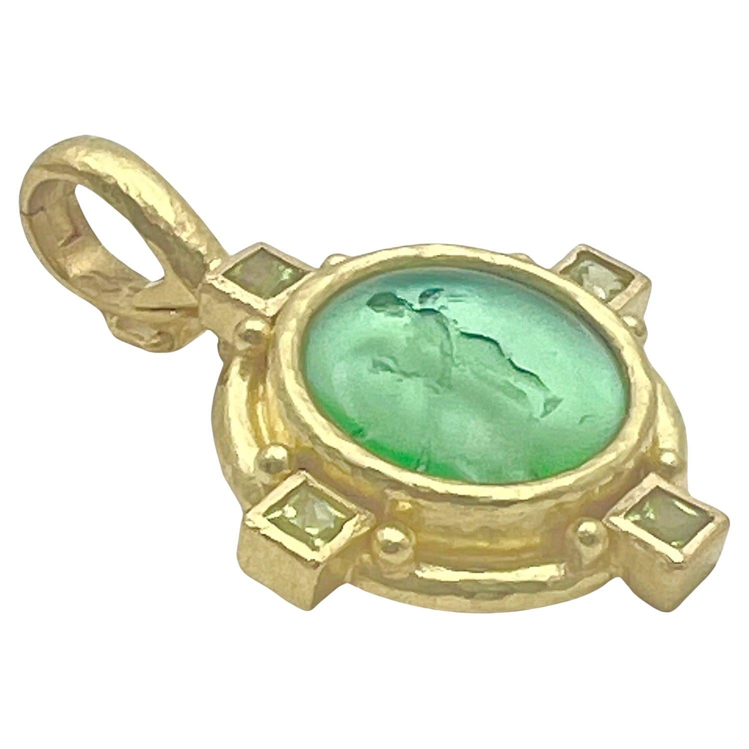 Ciondolo a intaglio di Elizabeth Locke, con vetro verde veneziano intagliato in un putto alato sostenuto da madreperla e incastonato in una montatura in oro giallo 19k martellato a mano.  La cornice è ulteriormente accentuata da quattro peridoti di