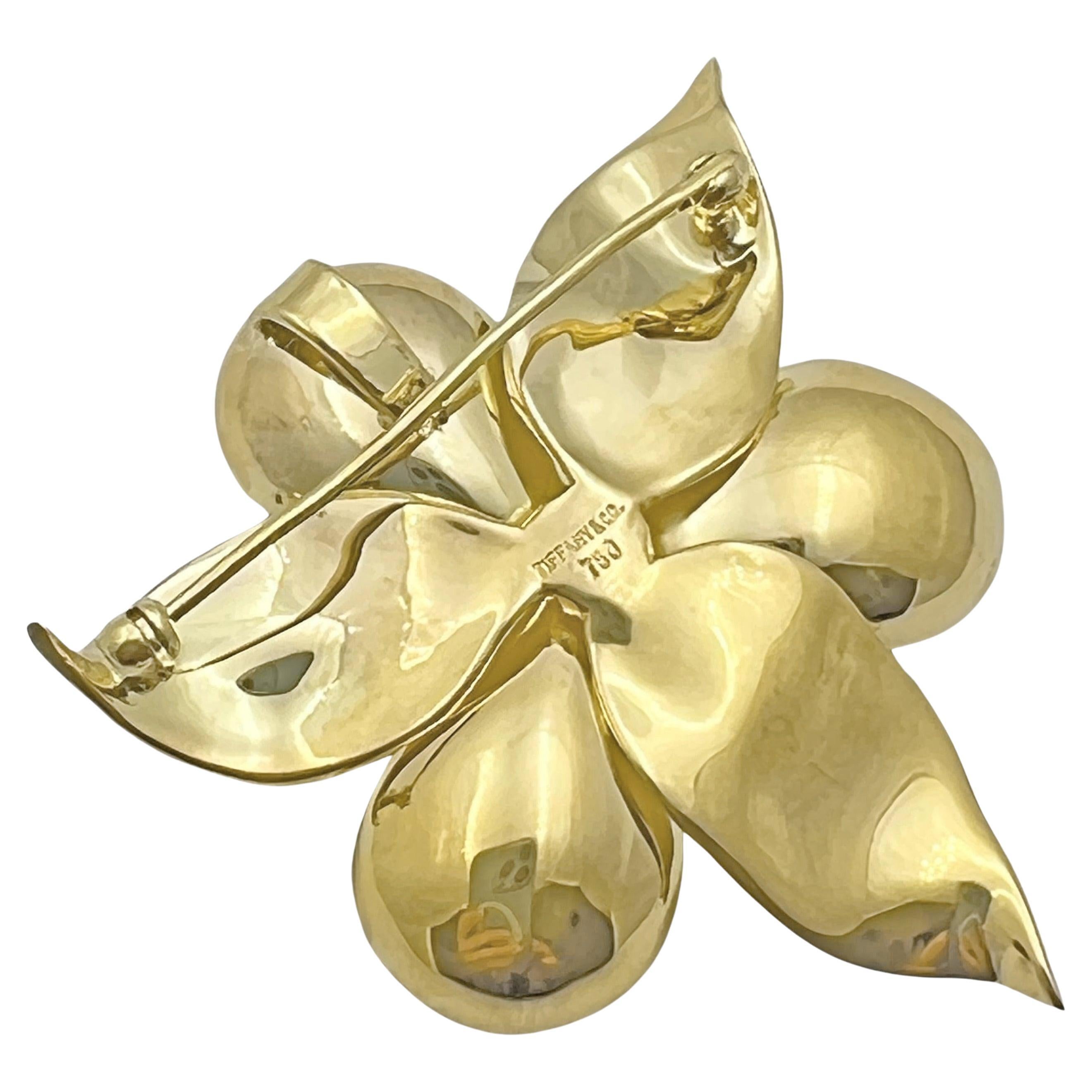 Dogwood flower blossom pendant brooch in 18 karat yellow gold with satin textured petals with curved up tips. The central pistil of the blossom is accented by seven round brilliant-cut diamonds weighing approximately 0.55 total carats.  Polished