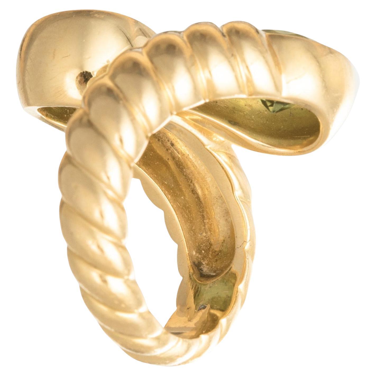 Anillo cruzado Verdura de oro amarillo de 18k engastado con peridoto verde vibrante redondo facetado a juego.  Peridotos de aproximadamente 7,8 mm de diámetro cada uno.  Montaje de diseño estriado pulido que mide 23,85 mm de ancho en la parte