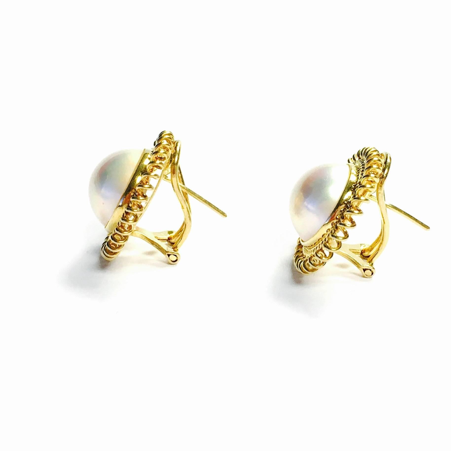Each earring features a 13 mm white cultured South Sea pearl with a pink over-tone and high luster, set within an 18K yellow gold sunburst style bezel. Post and omega backs. Each earring measures 22 mm in diameter. 
Weight: 12.1 grams