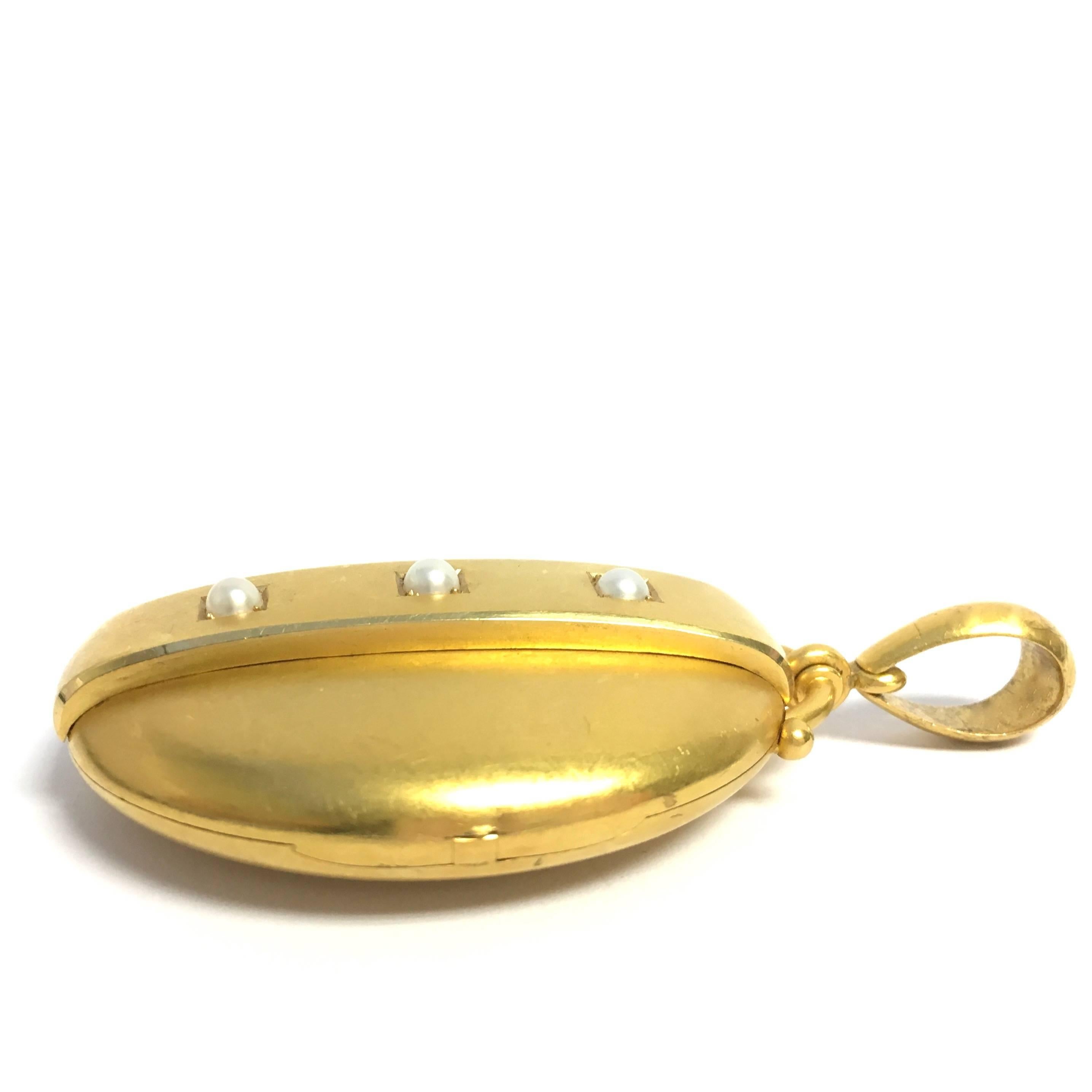 Large Victorian 14K yellow gold pendant featuring three-pearl set raised gold bar on the front. The single hinge design has room for relics or photos. Matte finish throughout. 
Measurements: 2 7/8