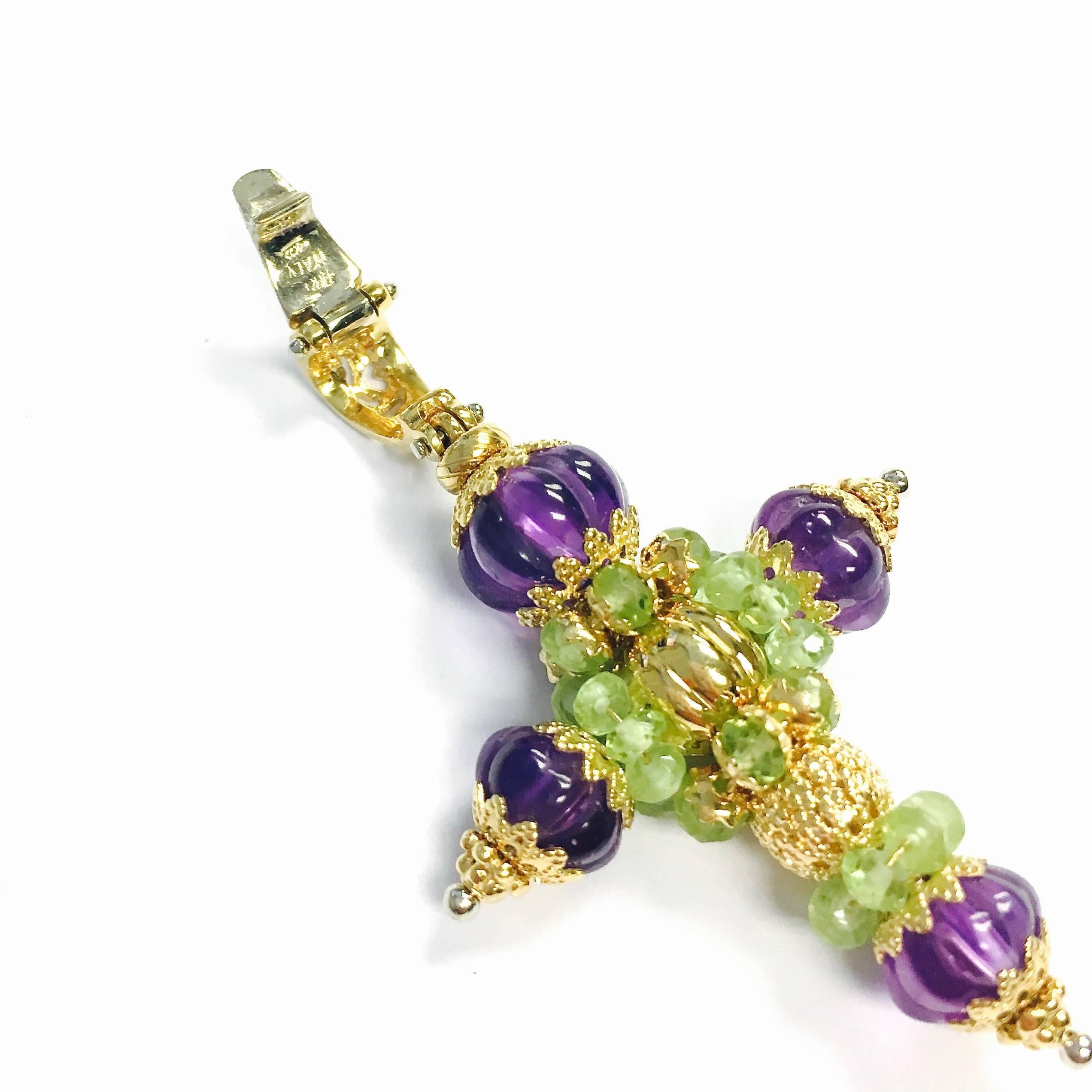 Unique 18K yellow gold cross pendant decorated with carved amethyst and faceted peridot beads. 
Measurements: 2 1/4" H x 1 5/16" W x 1/2" D
Weight: 10 grams