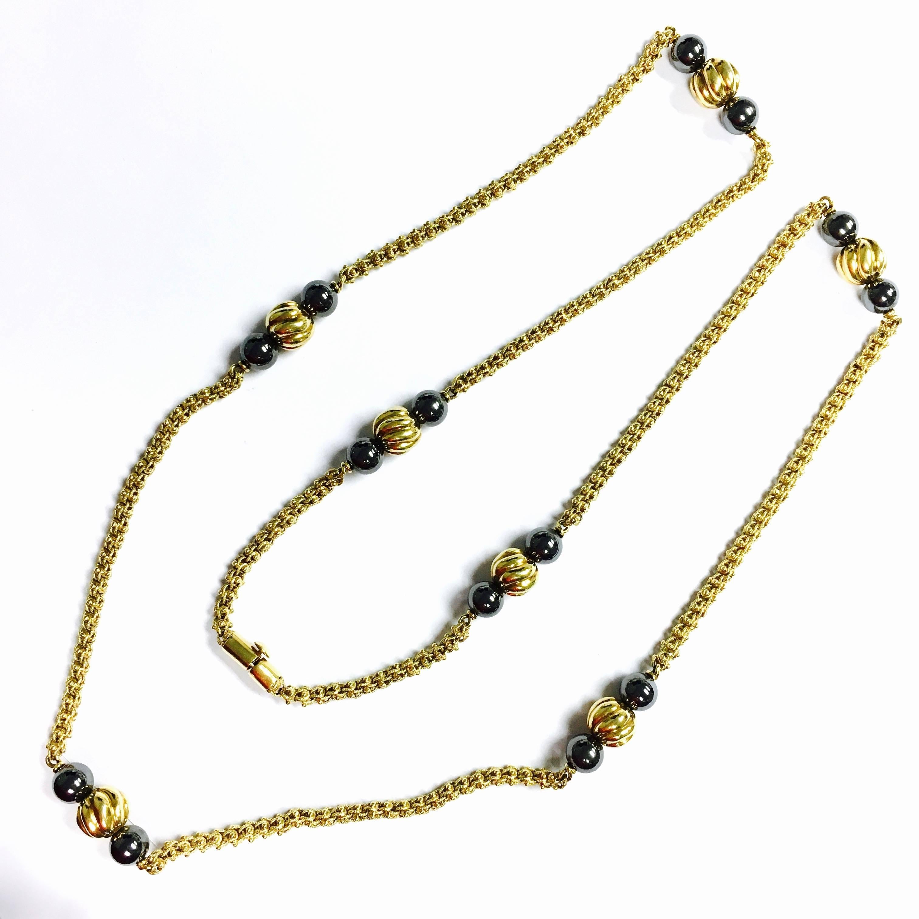 Crafted in 18K yellow gold, the chain features seven stations with two 8 mm hematite and on 10 mm gold beads.  35 inch long textured 4 mm wide chain.
Weight: 78.3 grams