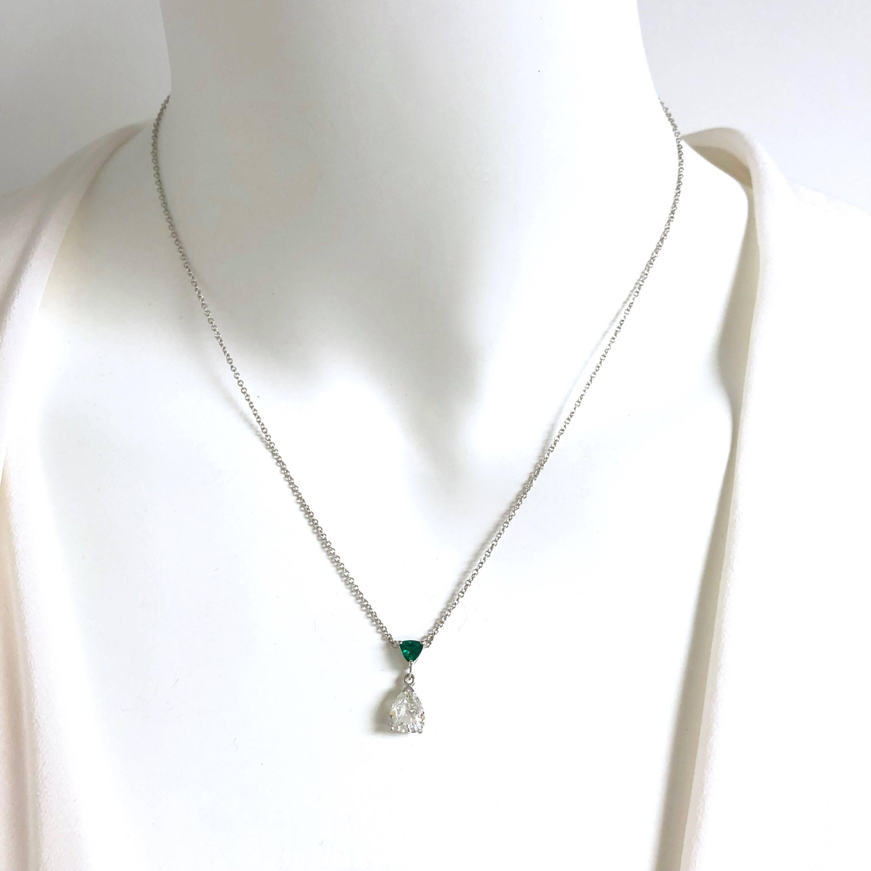 Crafted in 14K white gold, the necklace features a pear shape diamond solitaire supported by a triangle shaped vivid green natural emerald and a seventeen inch length rolo style chain terminating in s spring ring clasp.
Diamond: 0.90ct, Color: H,