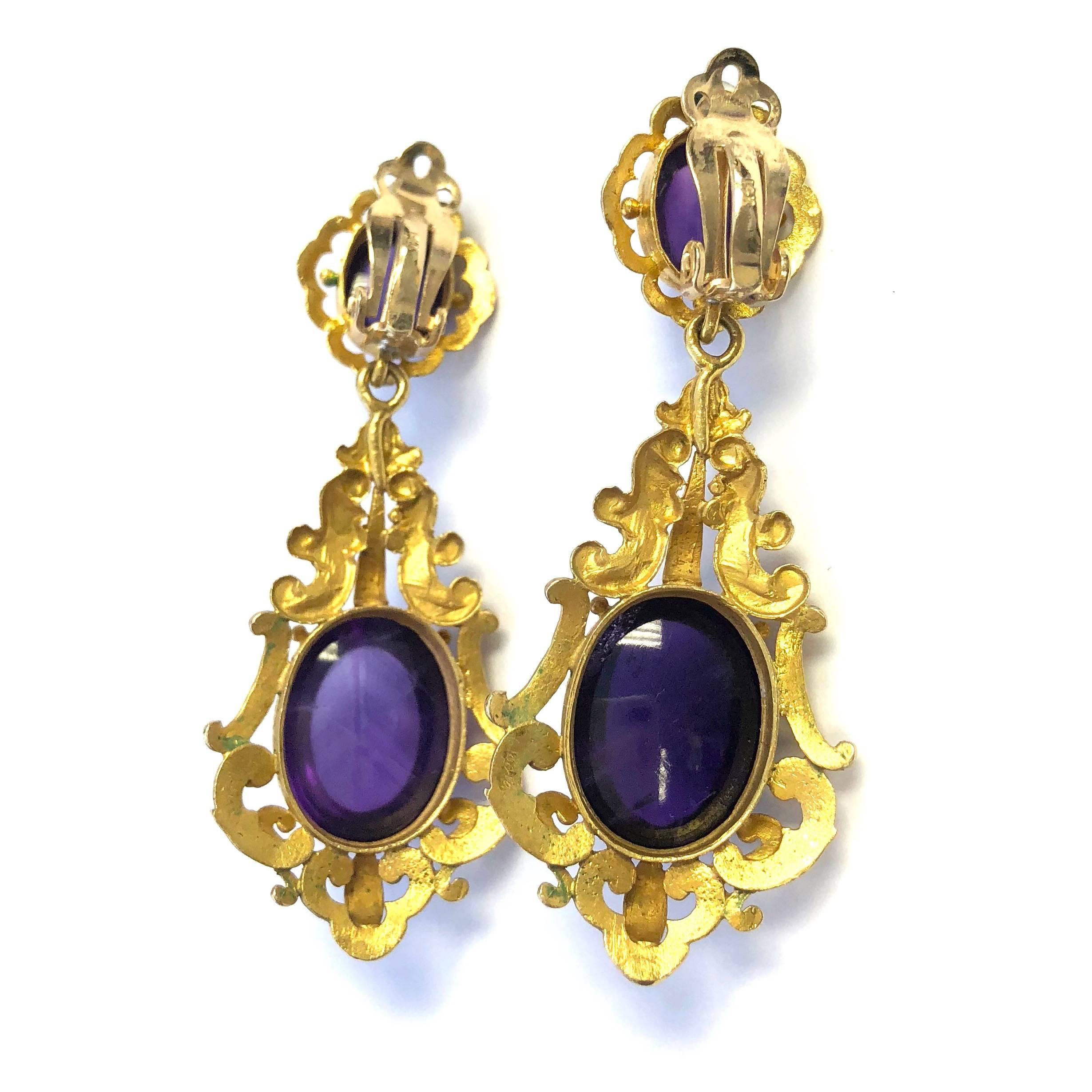 Victorian amethyst and 14K gold pendant earrings, with oval cabochon shaped amethyst drops below oval cabochon cut tops, both claw set to gold scrollwork frames of bold openwork design. Approximate total weight of 4 stones: 24 carats
Measurements: 2