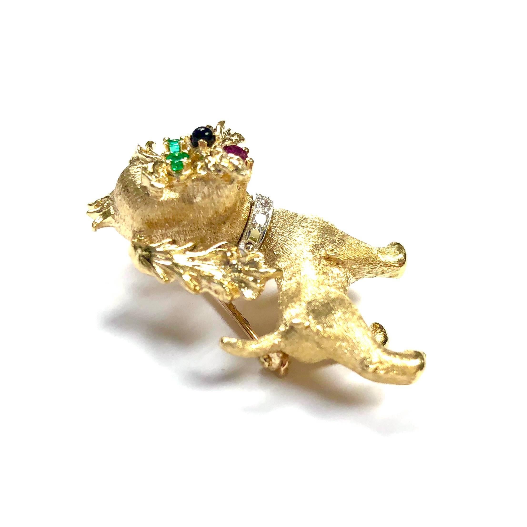 Crafted in 14K gold, featuring a dog accented with emerald eyes, a ruby in it's mouth and three diamonds set in it's white gold collar. 
Measurement: 1 1/8" H x 1 1/16" W
Marked: DAN FRERE  14K COPYRIGHT
Weight: 7.9 grams