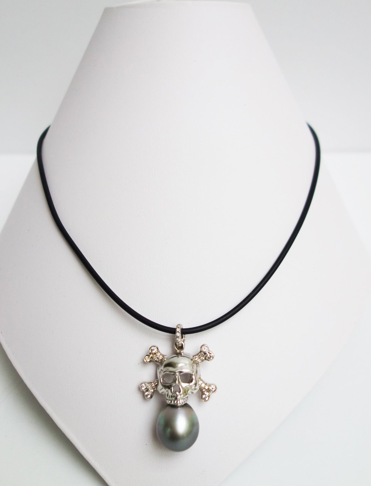 Featuring a 14mm cultured black Tahitian pearl supported by an 18K white gold diamond set skull pendant enhancer. Stamped 18K EC. Can be worn on a gold chain, leather cord or pearl strand.