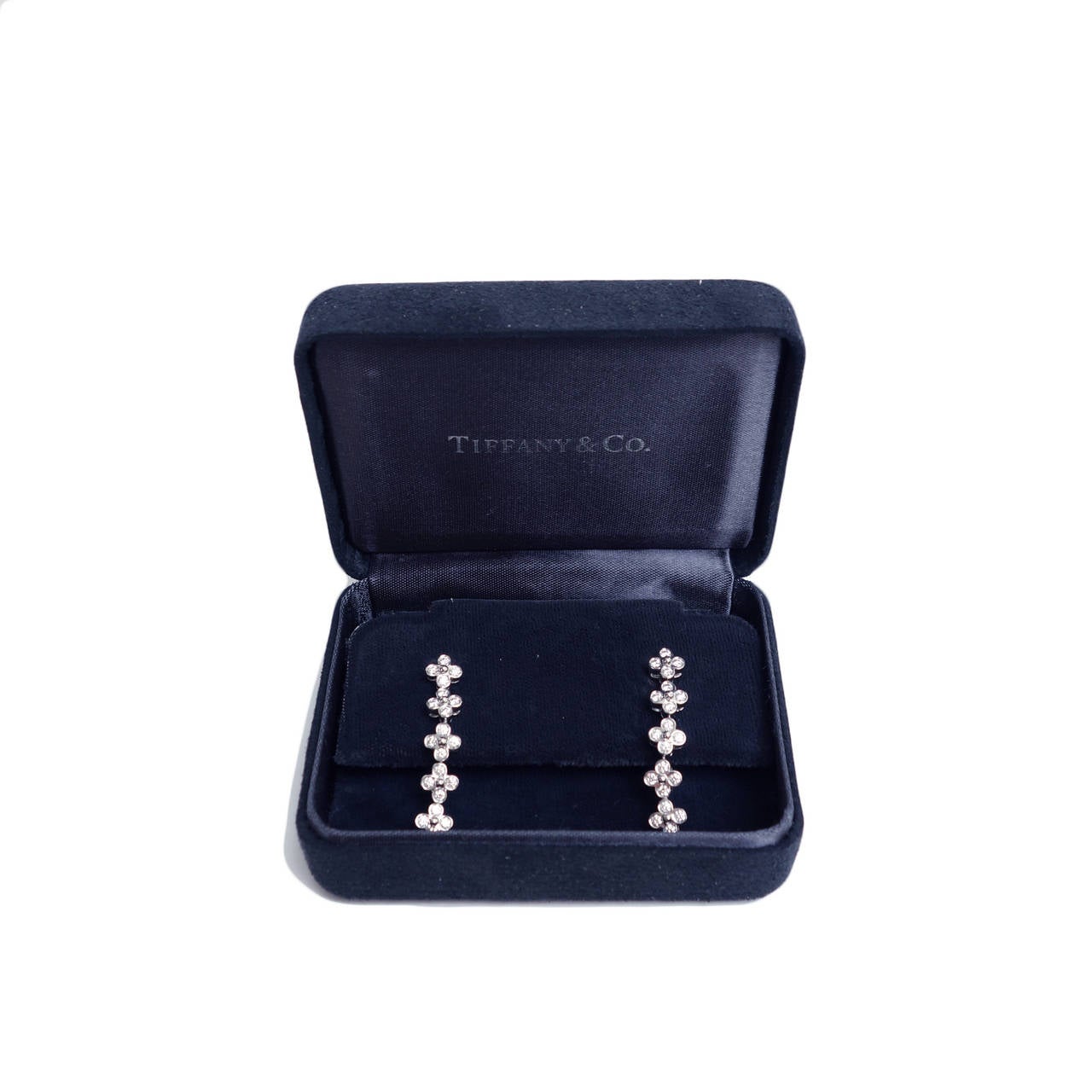 Tiffany & Co. Platinum Lace drop diamond earrings.  Each earring features 5 floret designs linked by small platinum jump rings which makes the earrings flexible.  There are 20 round brilliant cut diamonds in each earring. The total carat weight of
