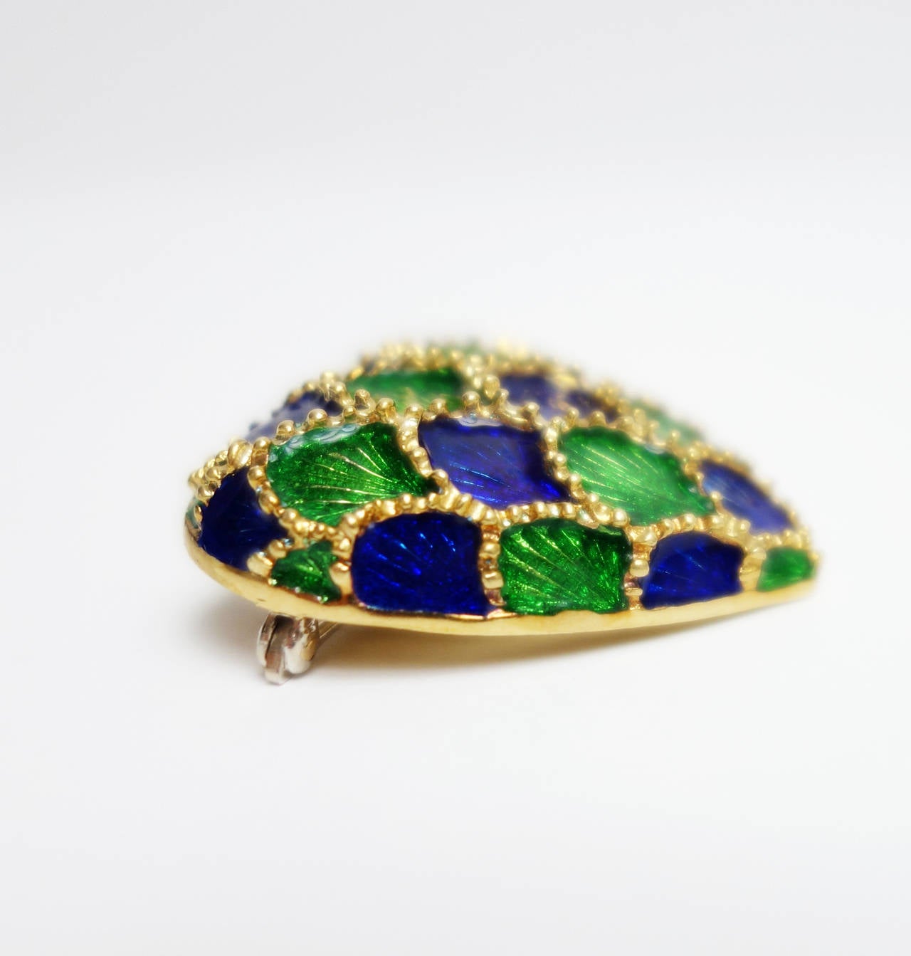 Tiffany&Co. 18k yellow gold pin with raised scalloped design featuring green and blue enamel. Excellent condition. 

Hight: 30mm or 1 3/8 inches
Width: 29mm or 1 1/4inches
Weight: 15.5 grams
Tested: 18k
Stamped: TIFFANY 18k