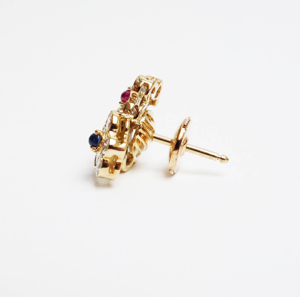 Each earring features a three-flower cluster set with emerald, ruby, sapphire and diamonds.