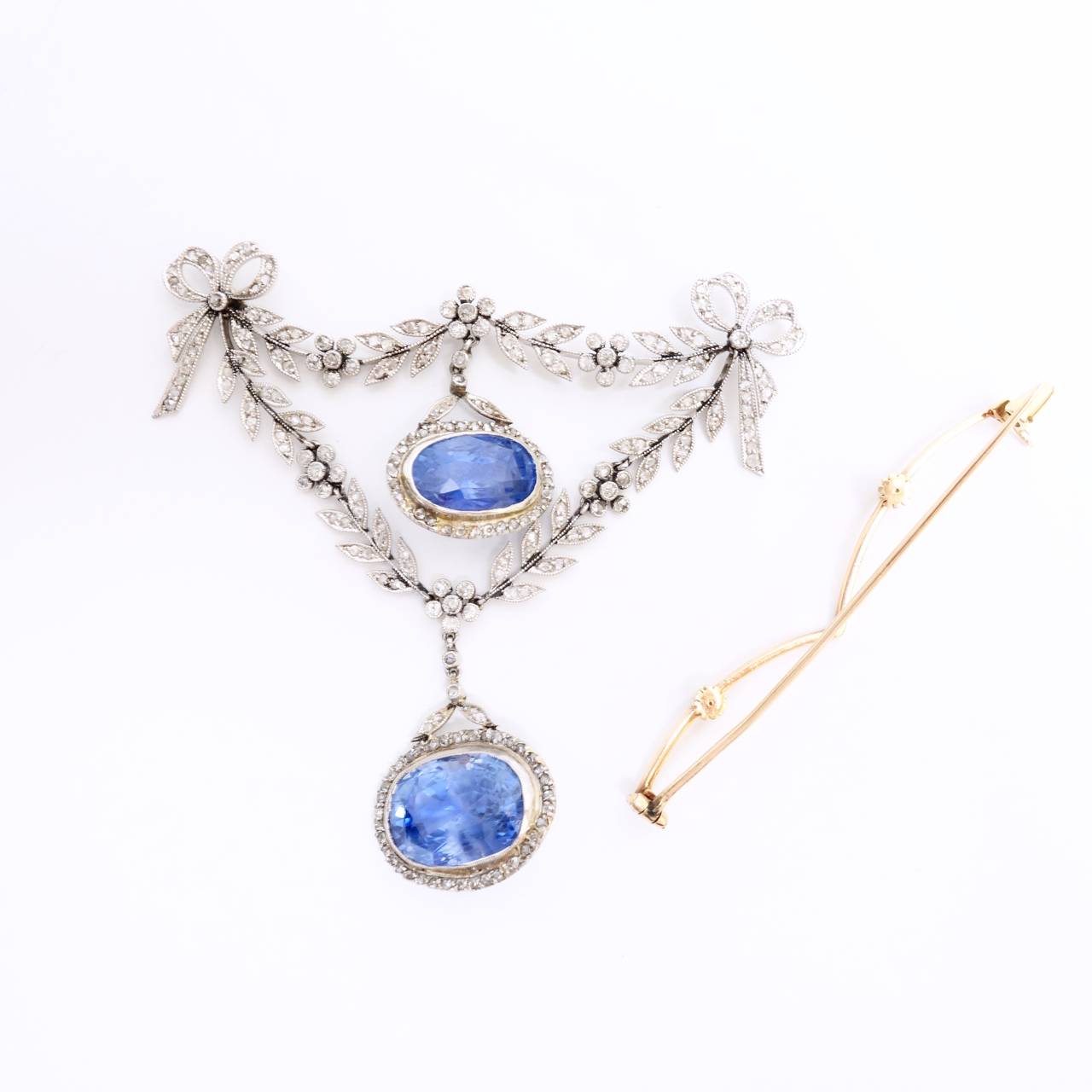 Fairy Unheated Ceylon Sapphire and Diamond brooch from the Belle Epoque era.  Circa 1905. In the garland style, designed as tied ribbon bows with scrolls and articulated floral swags, featuring two sapphire and diamond set drop pendants. The larger