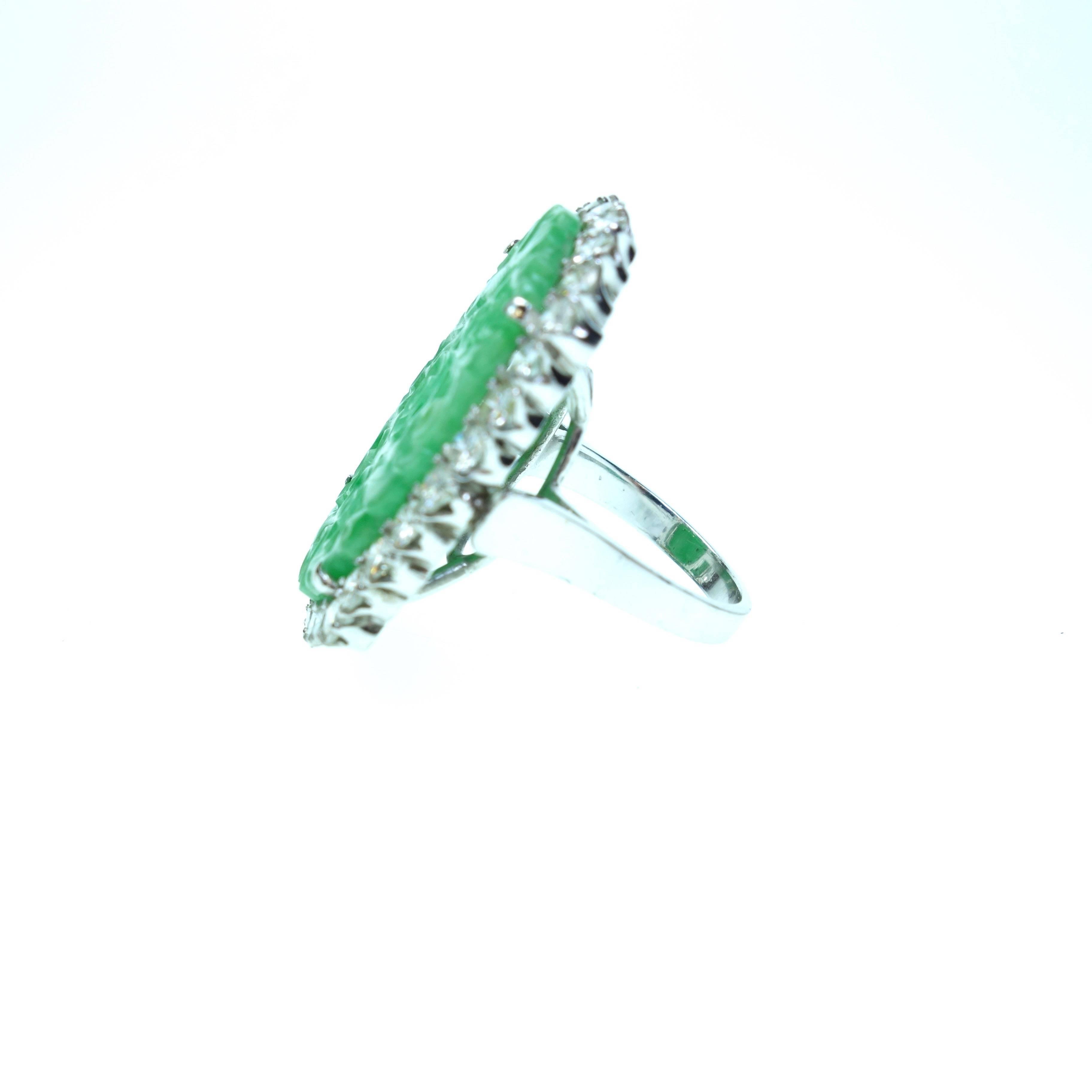Crafted in 18K white gold, the ring features an oval hand carved 29x20mm natural no treatment green jade (Gübelin Gem Lab Report# 16097316), surrounded by a bezel of thirty round brilliant cut diamonds, approximate total weight of 2.40ct. Color: