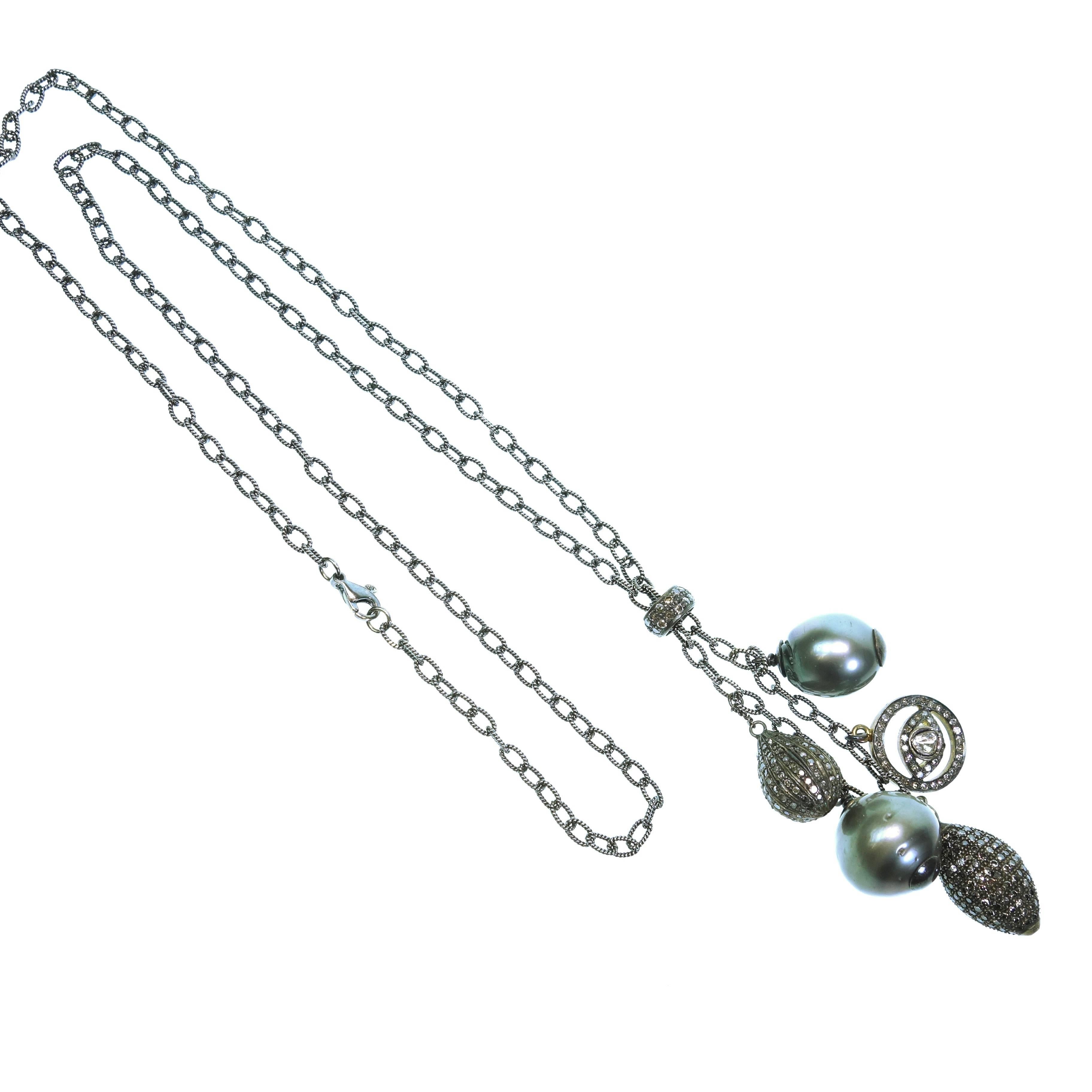 The  necklace features to baroque shape balck Tahitian pearls measuring 14.7mm and 18mm, one teardrop shape pave set diamond pendant in silver,  one elongated marquise shape pave set diamond pendant in silver and one diamond set evil eye pendant in