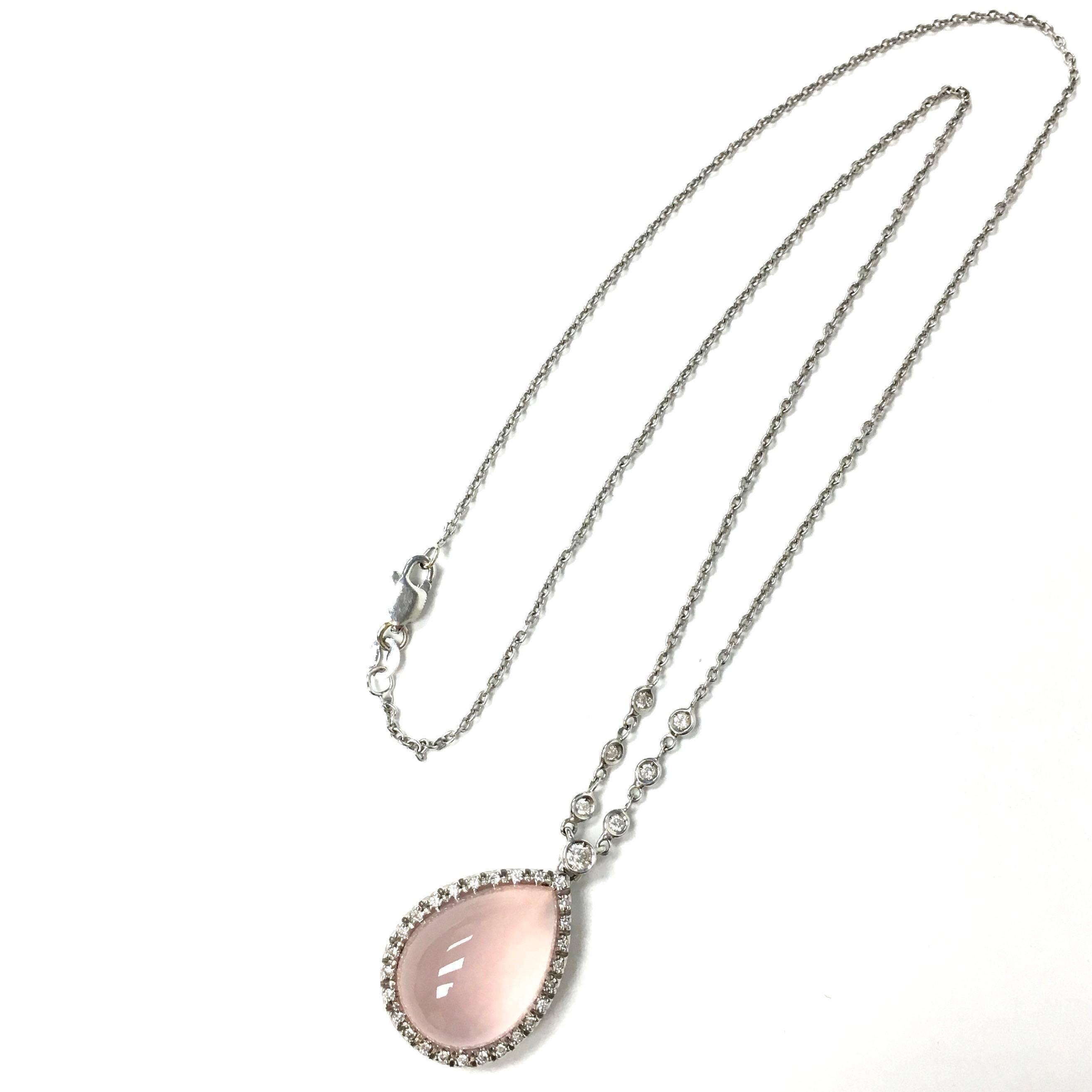 Favero stationary pendant necklace. Crafted from 18K white gold, featuring a teardrop shape rose quartz cabochon approx. 10.0ct, set within a bezel of diamonds, supported by a 16 inch length roll style chain set with seven bezel set round brilliant