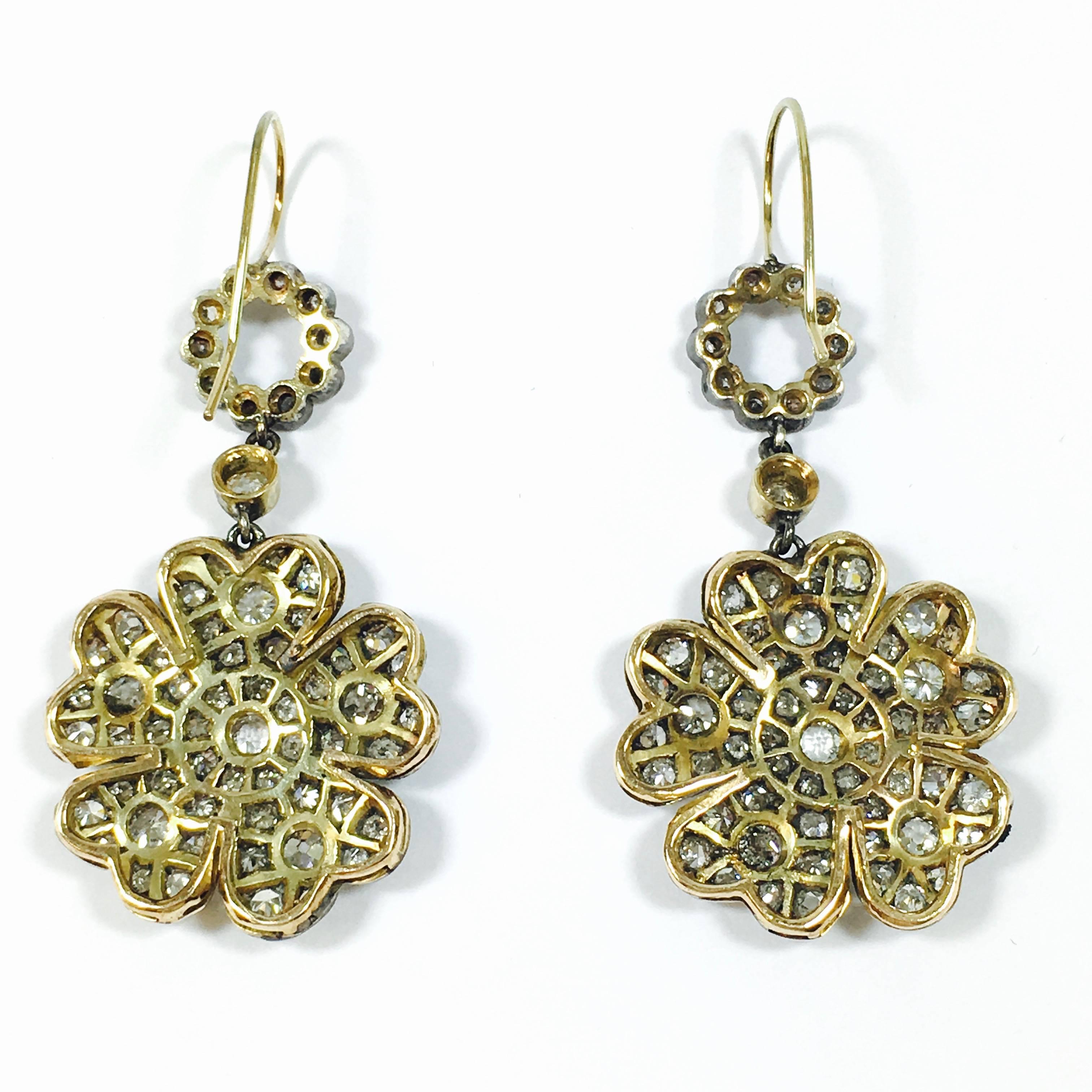 Amazing flower earrings crafted from 14K yellow gold and silver, set with 6 carats of round diamonds. Each earring features 7 individually set old European cut diamonds in yellow gold bezels, and 59 bezel and bead set diamonds.
The silver topping