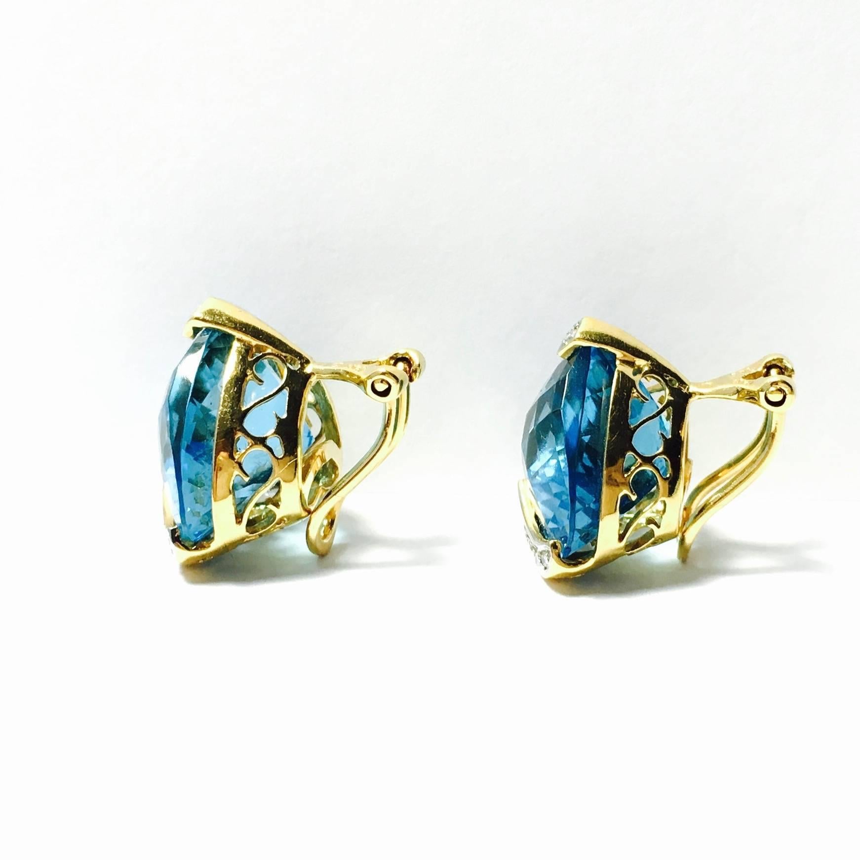 Gorgeous 18K yellow gold clip-on earrings set with neon blue checker board cut heart shaped topaz solitaires, accented with diamonds. Each topaz measures 15x16mm. Approximate total weight of  the two stones: 34ct.
22 round brilliant cut diamonds,