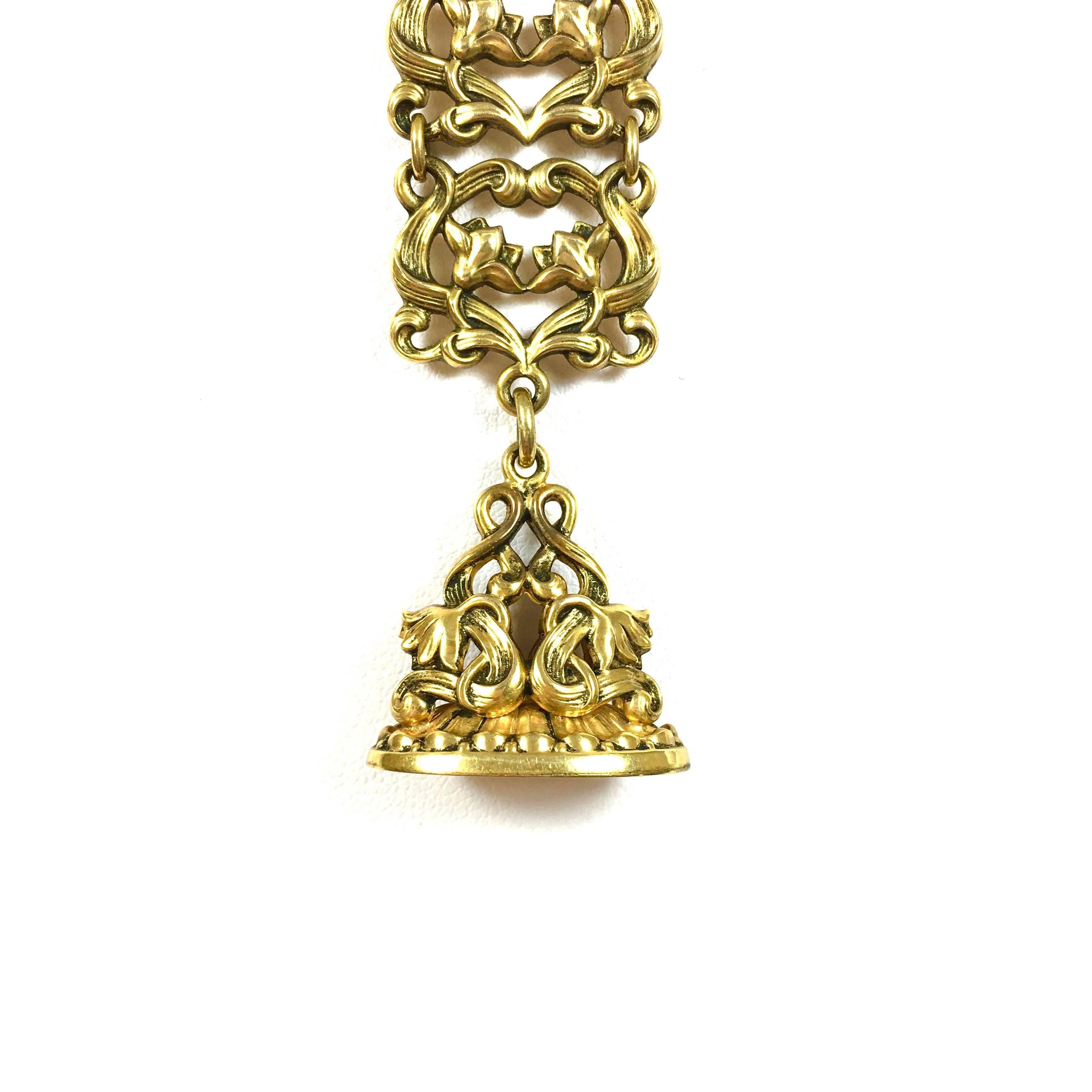 Amazing Victorian piece crafted in 10K yellow gold, featuring an open work scroll design wax seal stamp supported by an 18 mm wide gold ribbon and a brooch with black enamel and gold tassel. 
Length: approximately 5 inches
Weight: 15.8 grams