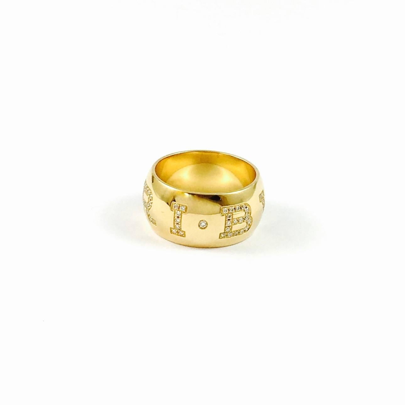 Bvlgari Monologo ring, featuring pave' set diamonds to spell out the Bvlgari signature around the ring, made in 18k yellow gold. 
Width: 10 mm
Weight: 13.4 grams
Size: 54  US  approx. 6.5  (This band fits approximately two European sizes tighter