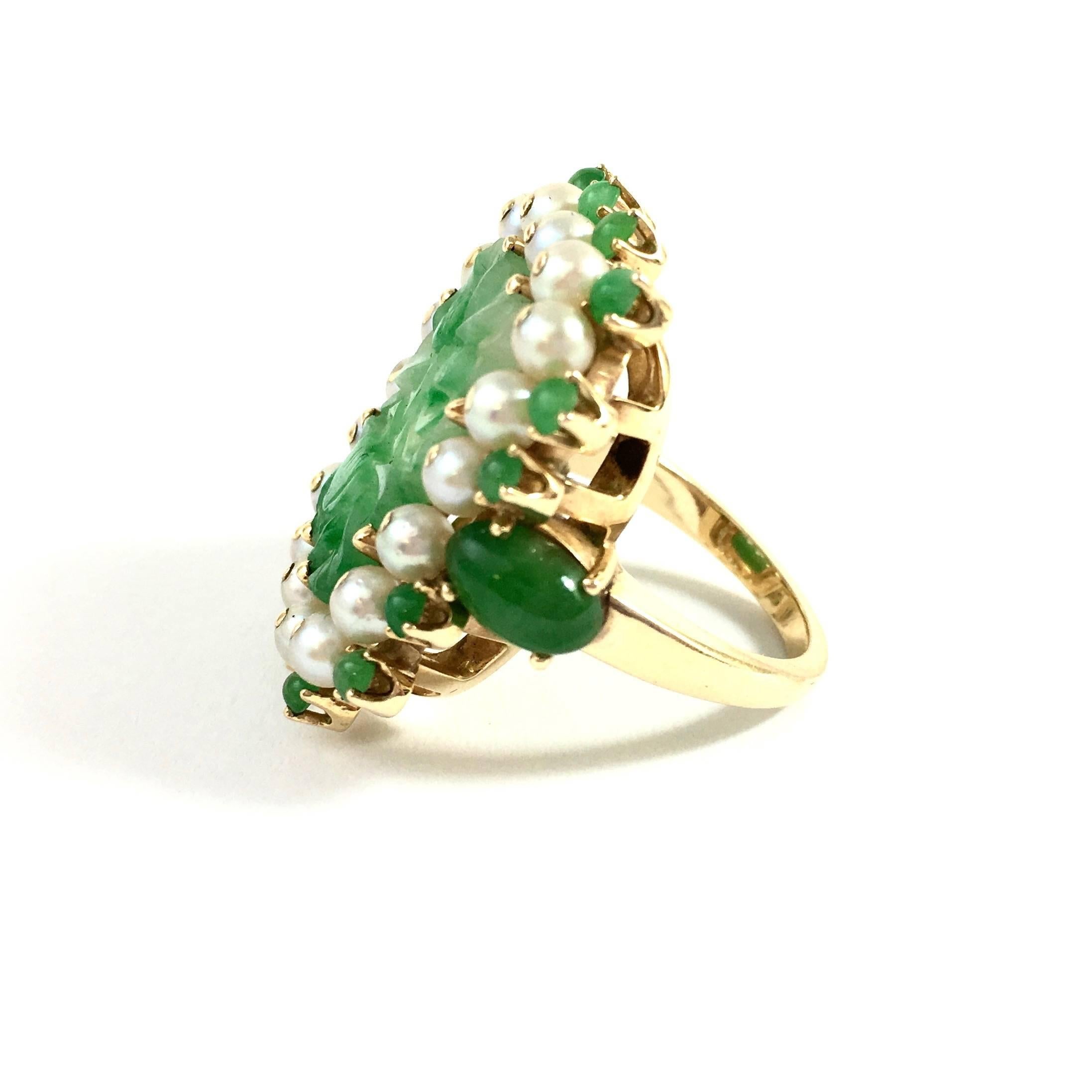 14K yellow gold ring, featuring a 17x11mm rectangular natural geen jade in the center, framed by an inner bezel of 3 mm cultured pearls and an outer bezel of 2 mm jade beads and 7.5x5mm oval cabochons on the shoulders. 
The front of the ring