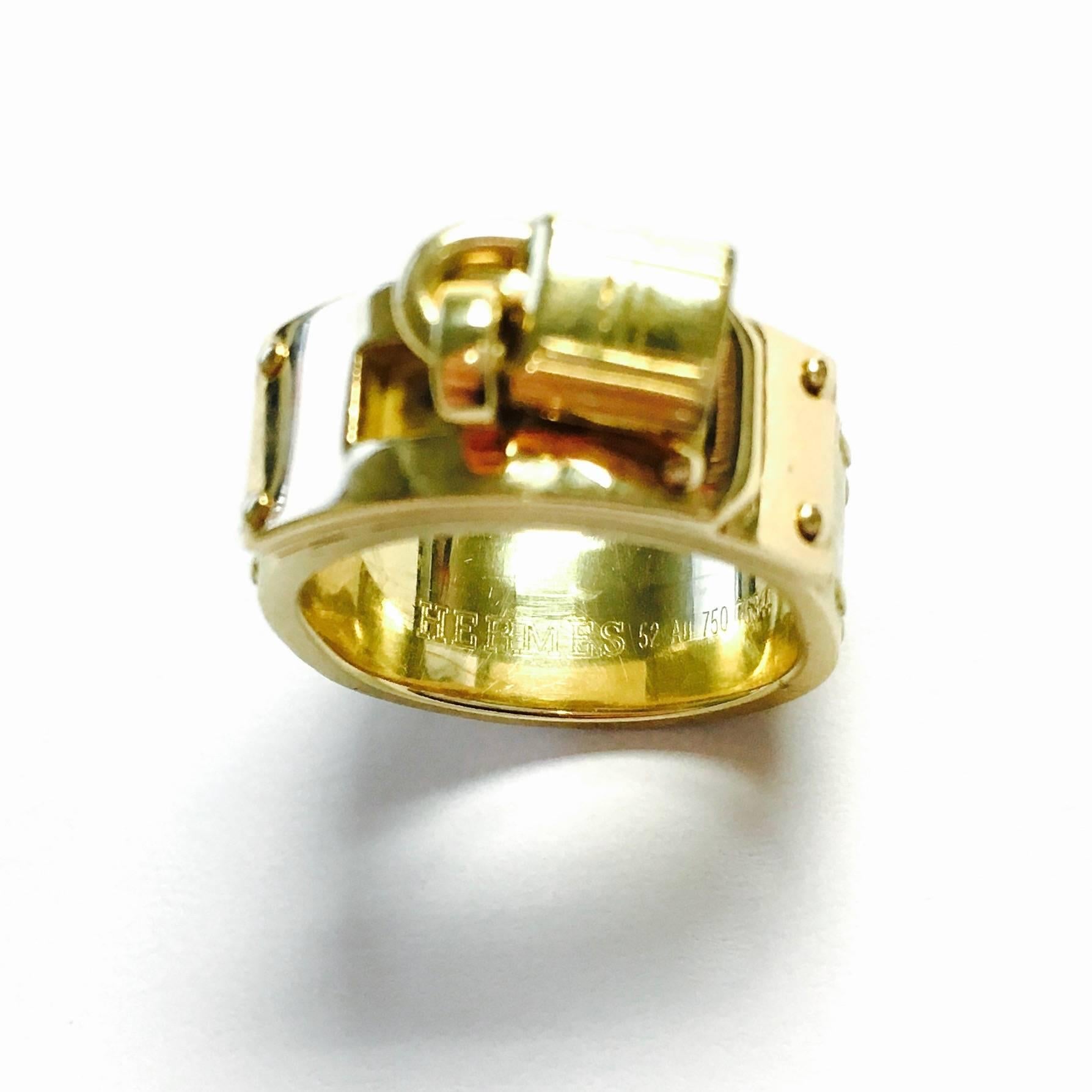 Crafted from solid 18kt yellow gold in a polished and satin finish from Hermes fashion house, the 7 millimeter wide band boast a stitch design following round the the edge of the band. The front is a polished gold slide bolt with the padlock.