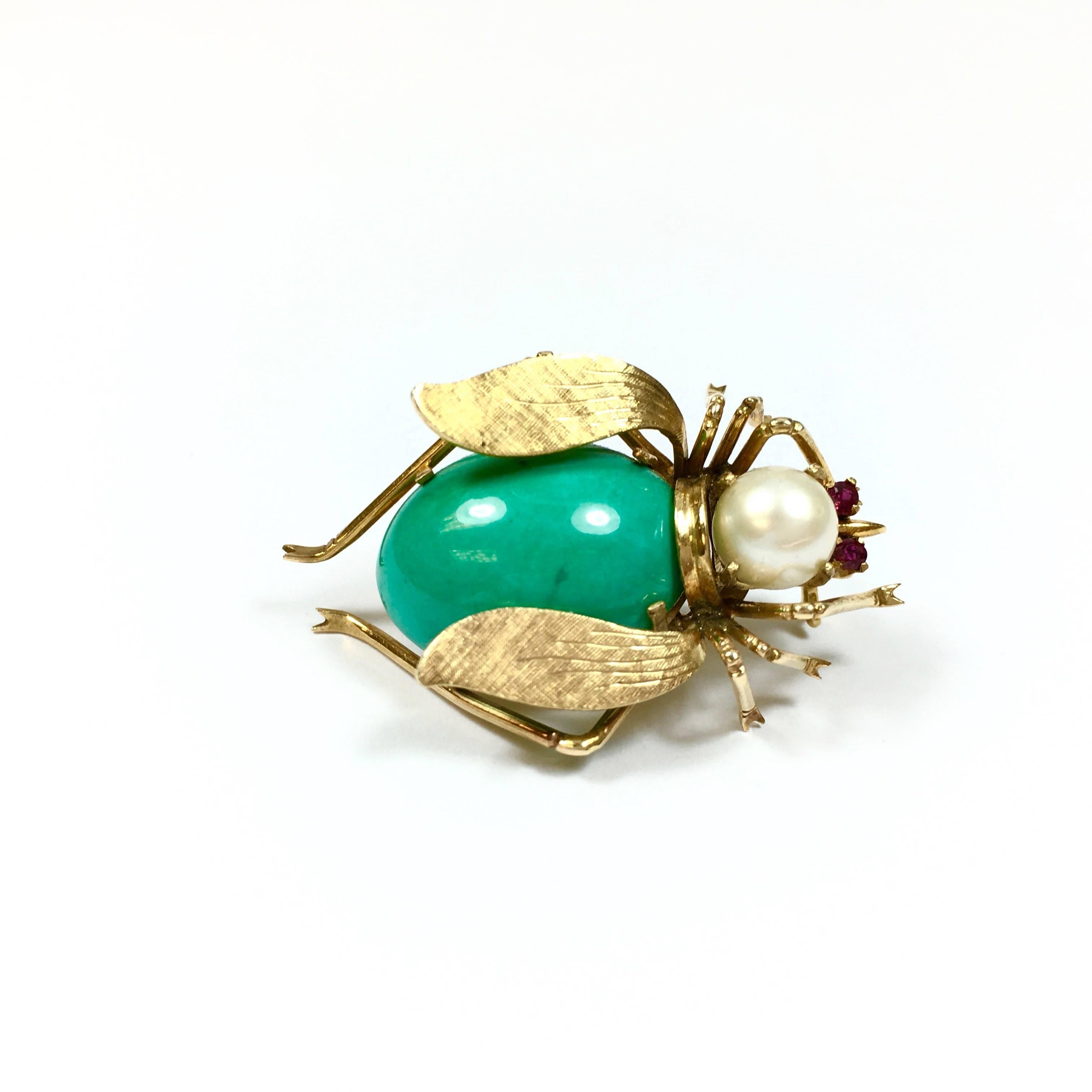 Crafted from 18K yellow, the lower body part is set with a 20 x 17 mm oval cabochon turquoise, the head with a 7 mm white cultured pearl, and the eyes are set with 2mm round natural rubies. 
The brooch measures: 38 mm L x 25 mm W
Weight: 9.6 grams