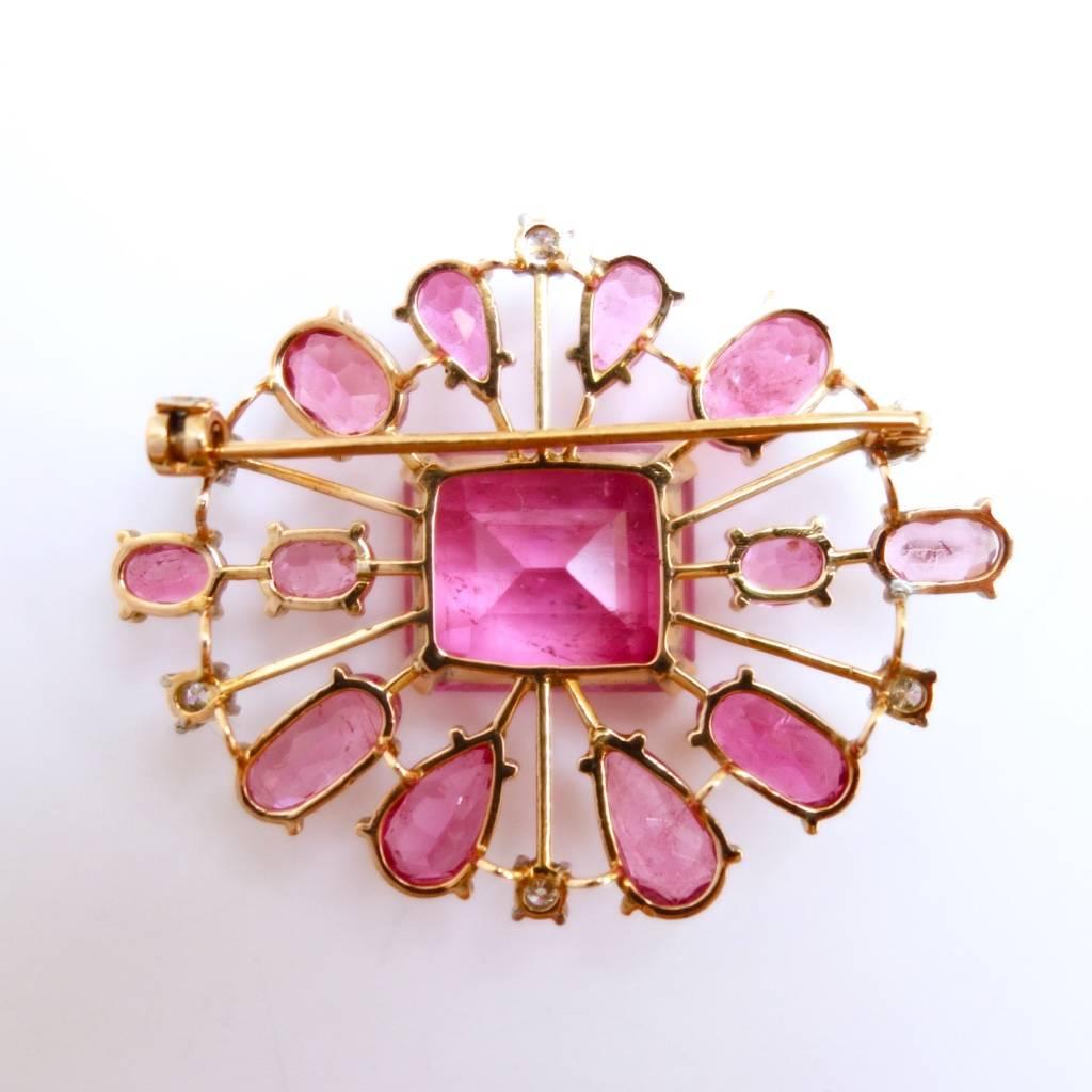 Gorgeous pink tourmaline and diamond brooch from the 1940s. 
The center stone is a 16.6 x 14.2 x 10.3 mm rectangular step cut pink tourmaline, approximate weight of 15.0ct, surrounded by twelve oval and pear shape pink tourmalines, approximate