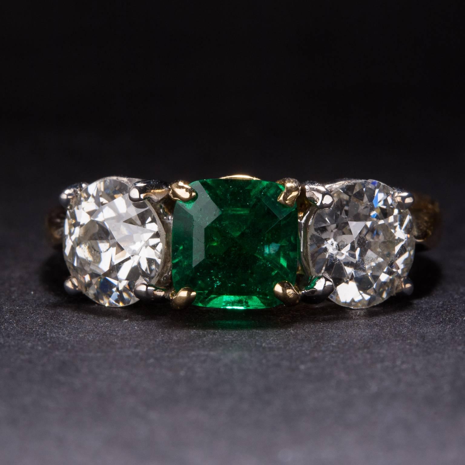 This gorgeous ring includes a 1.09 carat center emerald and two accent diamonds weighing a total of 1.82 carats. The mounting is crafted in 18k yellow gold and 18k white gold and it is currently size 6.