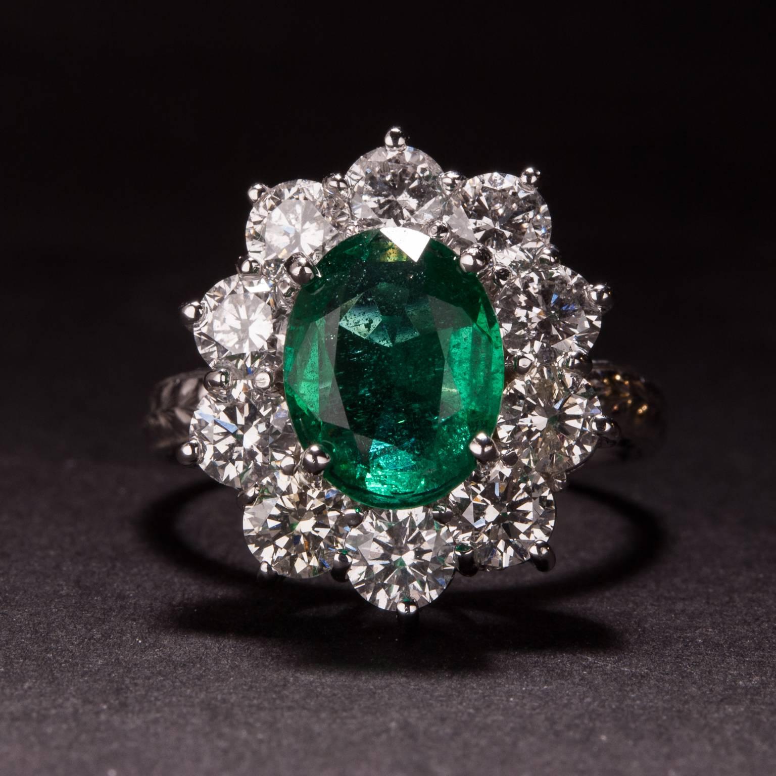 This lovely ring features a 2.68 carat center emerald that is surrounded by 10 accent diamonds weighing a total of 2.01 carats. The 18k white gold mounting has intricate engraved details and is currently size 7.
