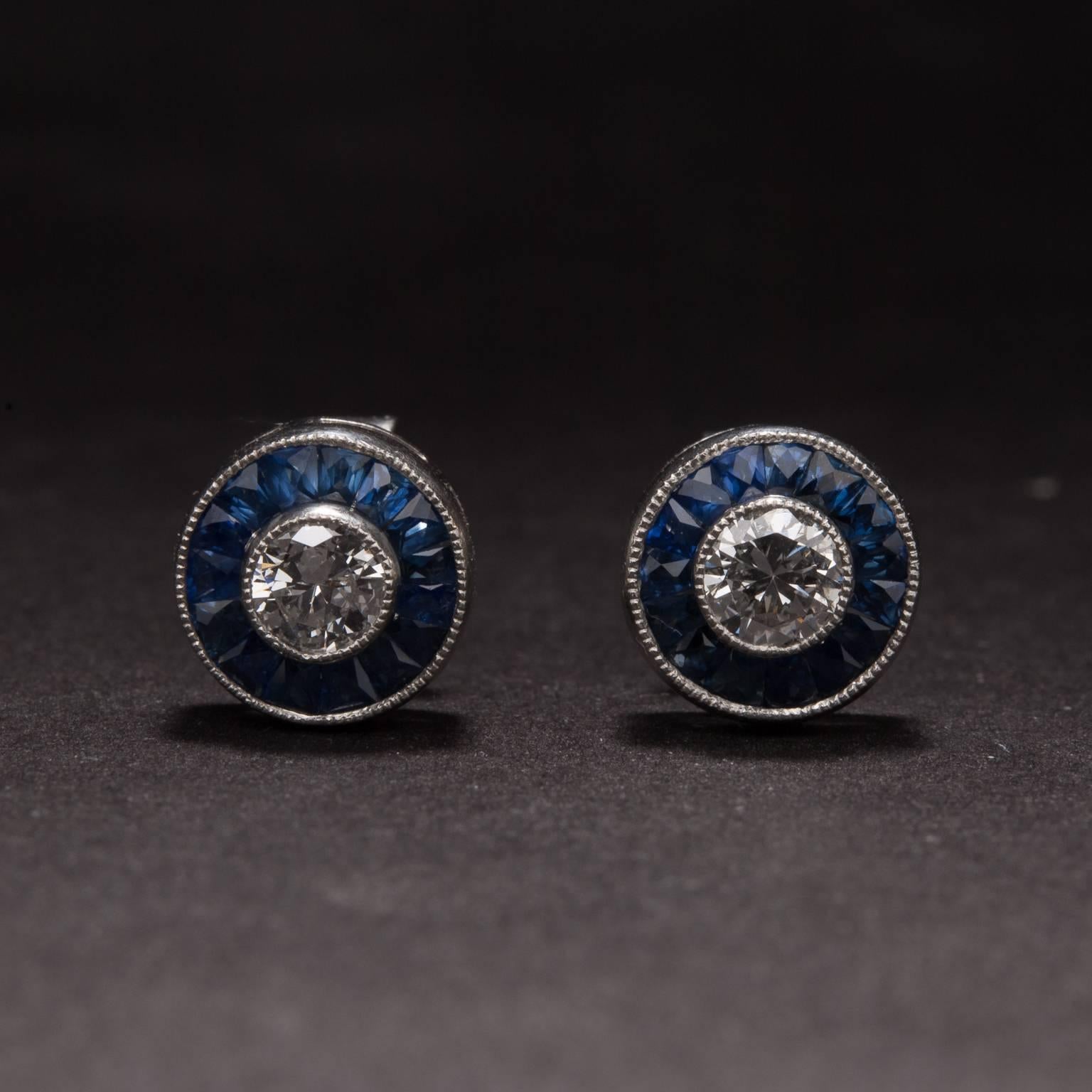 This lovely pair of stud earrings features .40 total carats of diamonds and .50 total carats of french cut channel set sapphires. These earrings are made in platinum and measure 7.8 mm in diameter.