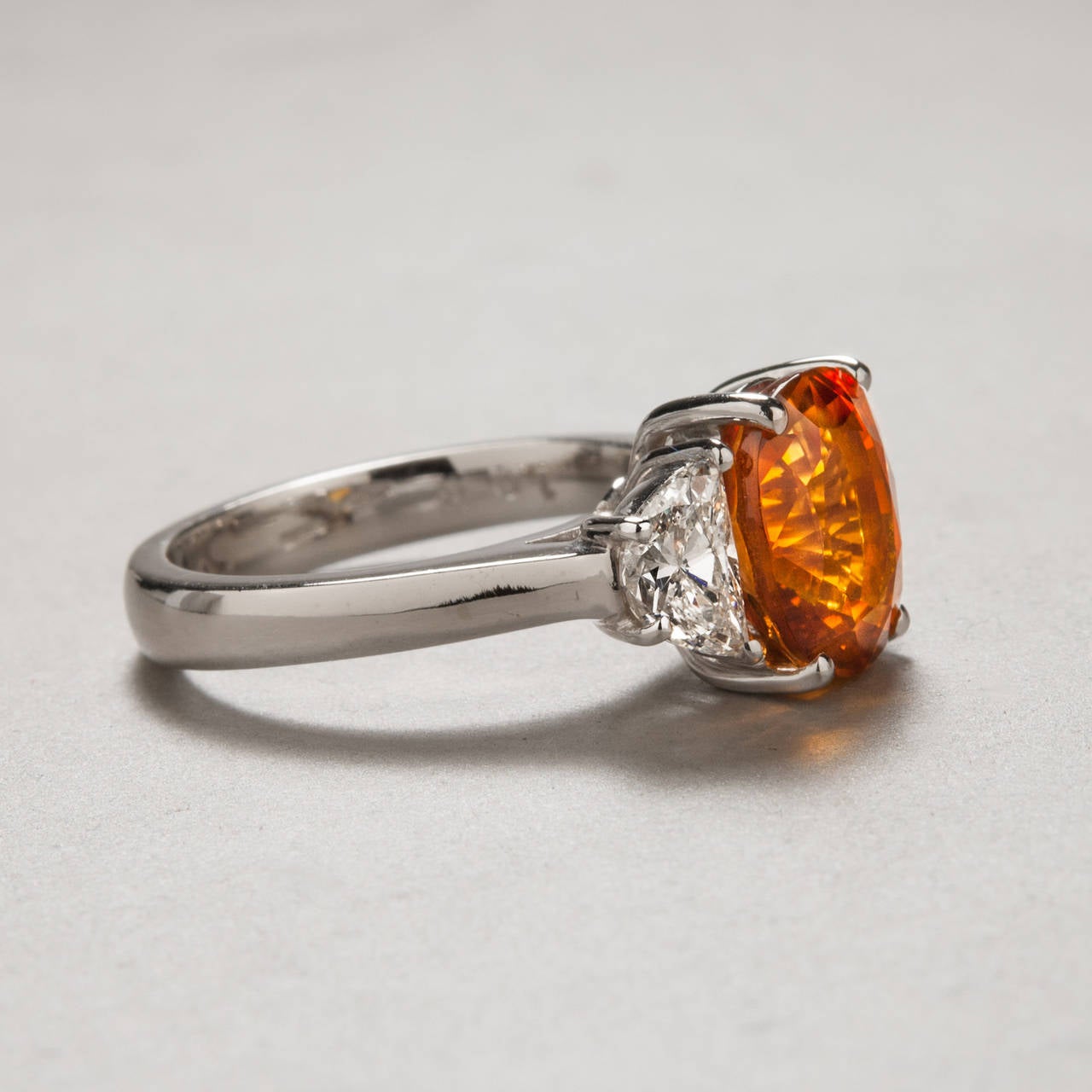 An extraordinarily vibrant orange sapphire sparkles at the center of this 18k white gold ring. The 4.97 carat orange sapphire is accented by two diamonds weighing 1.03 carats total. This Italian made piece has a unique and elegant look.