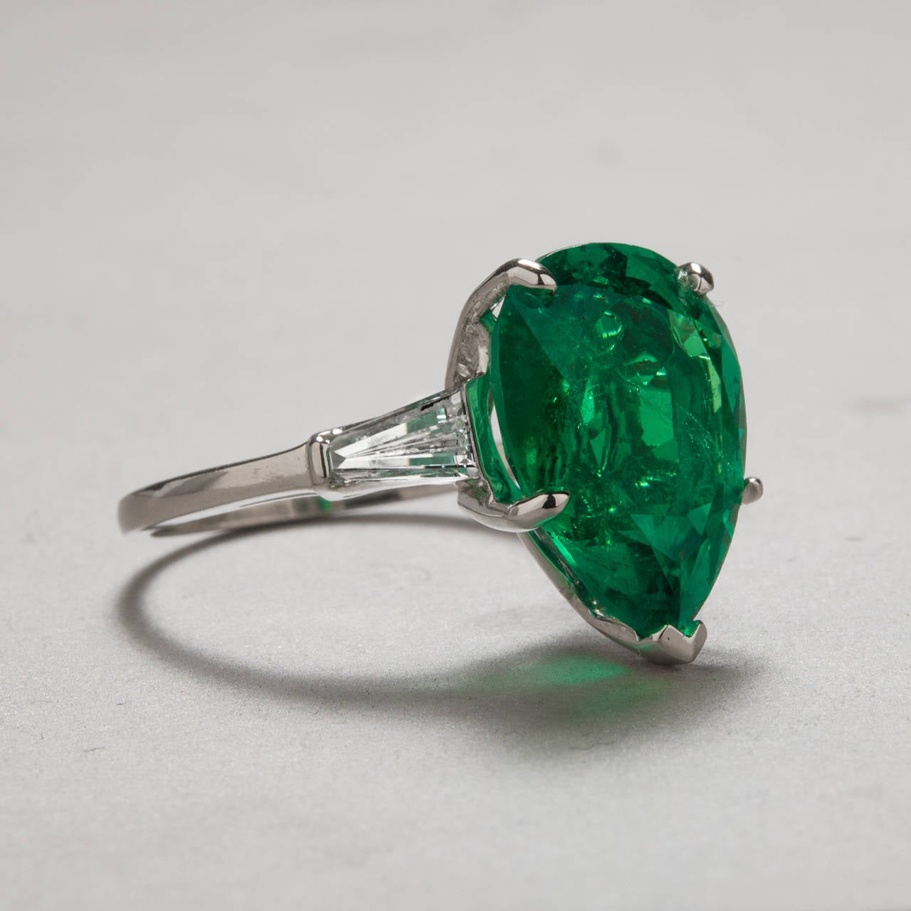 A stunning pear shaped emerald ring with two tapered baguette diamonds. At 6.82 carats, this GIA certified Columbian emerald is very clean especially considering its substantial size. The ring is crafted in platinum and the side diamonds weigh a